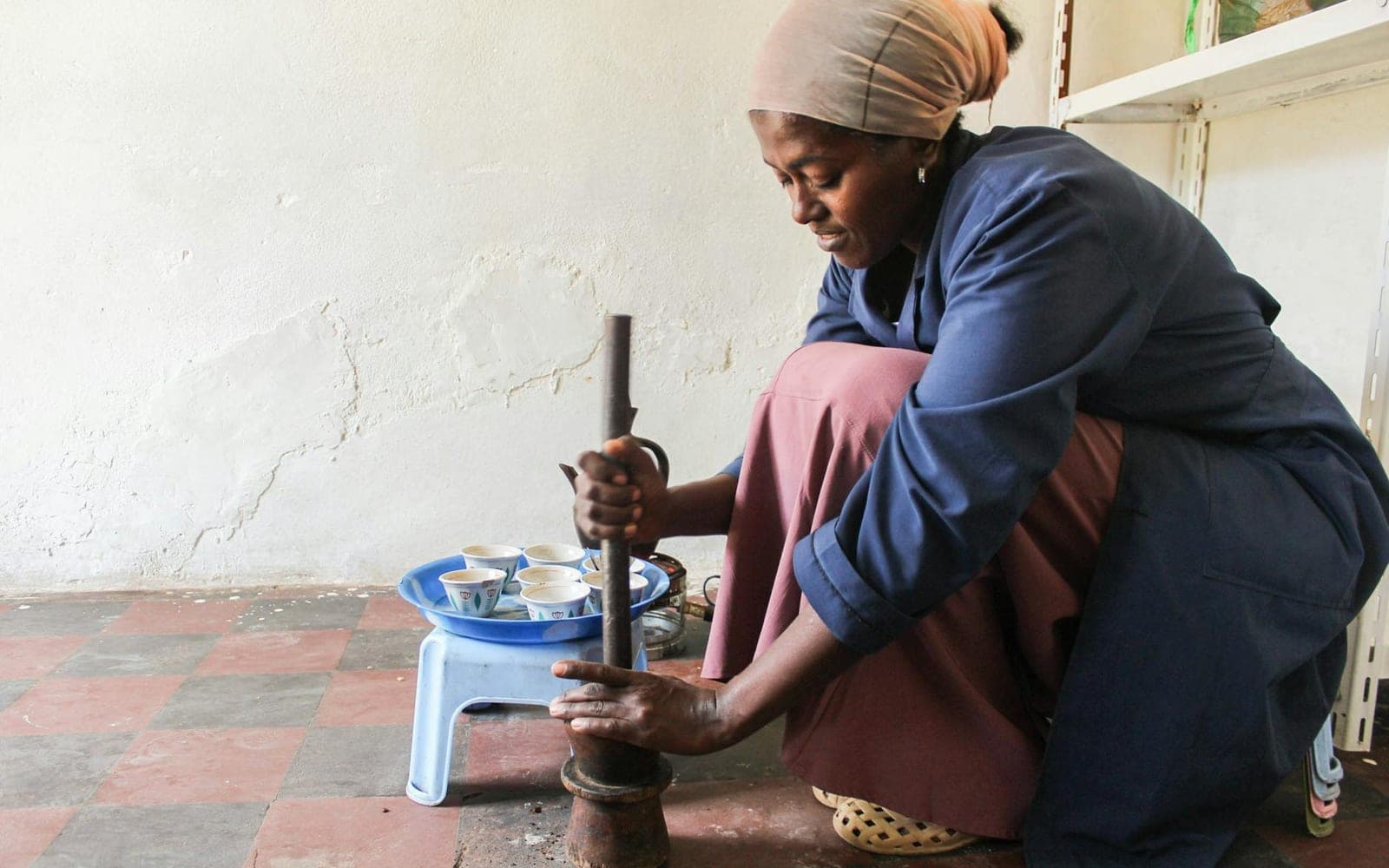 Ethiopian coffee ceremony preparation with coffee being ground by hand