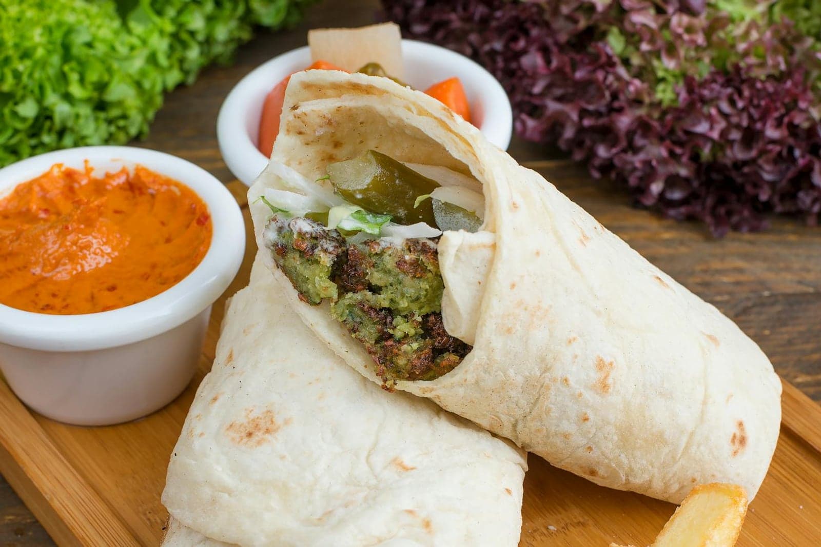 Falafel pita wrap with sauce, vegetables, and crisp falafel filling