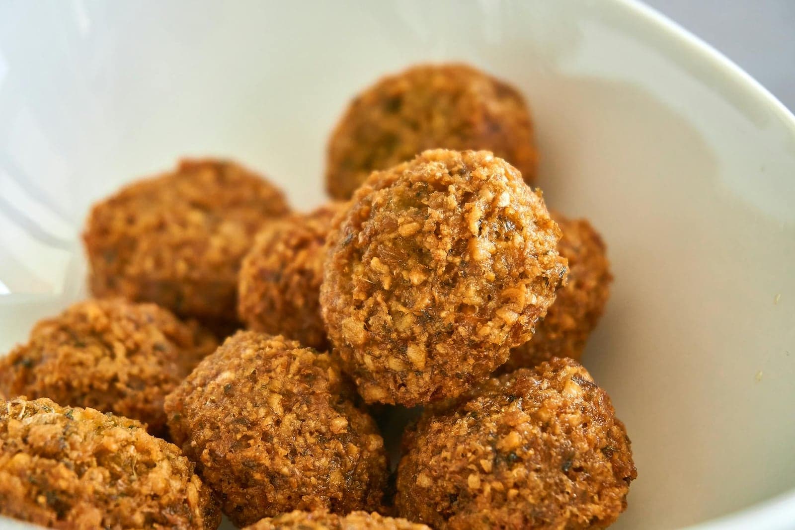 Falafel wrap components with crisp falafel balls in a white bowl