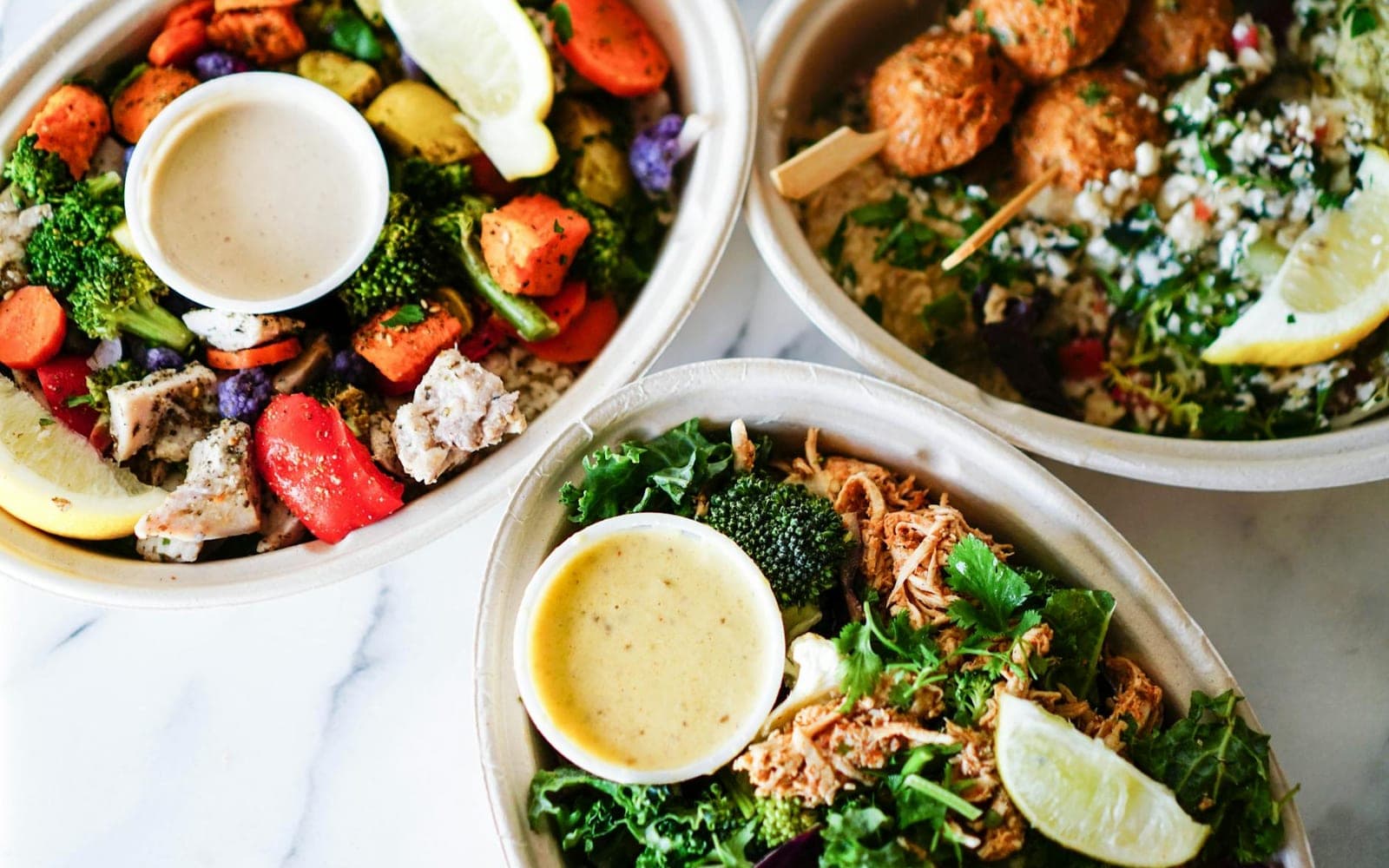 Farro salad with roasted vegetables, greens, and dressing in meal bowls