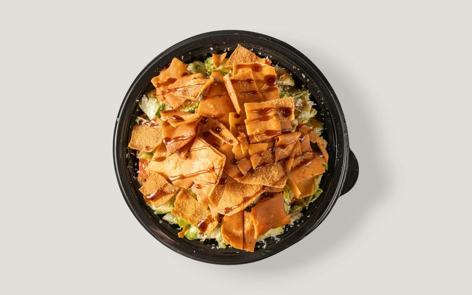 Fattoush crouton salad with crisp pita pieces, vegetables, and dressing in a black bowl
