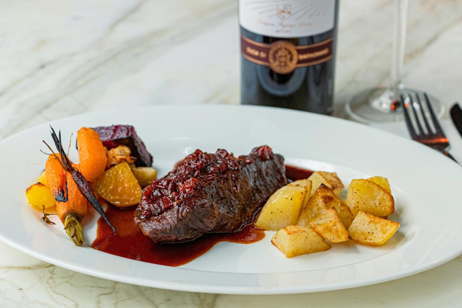 Filet mignon with red wine sauce, roasted potatoes, vegetables, and wine