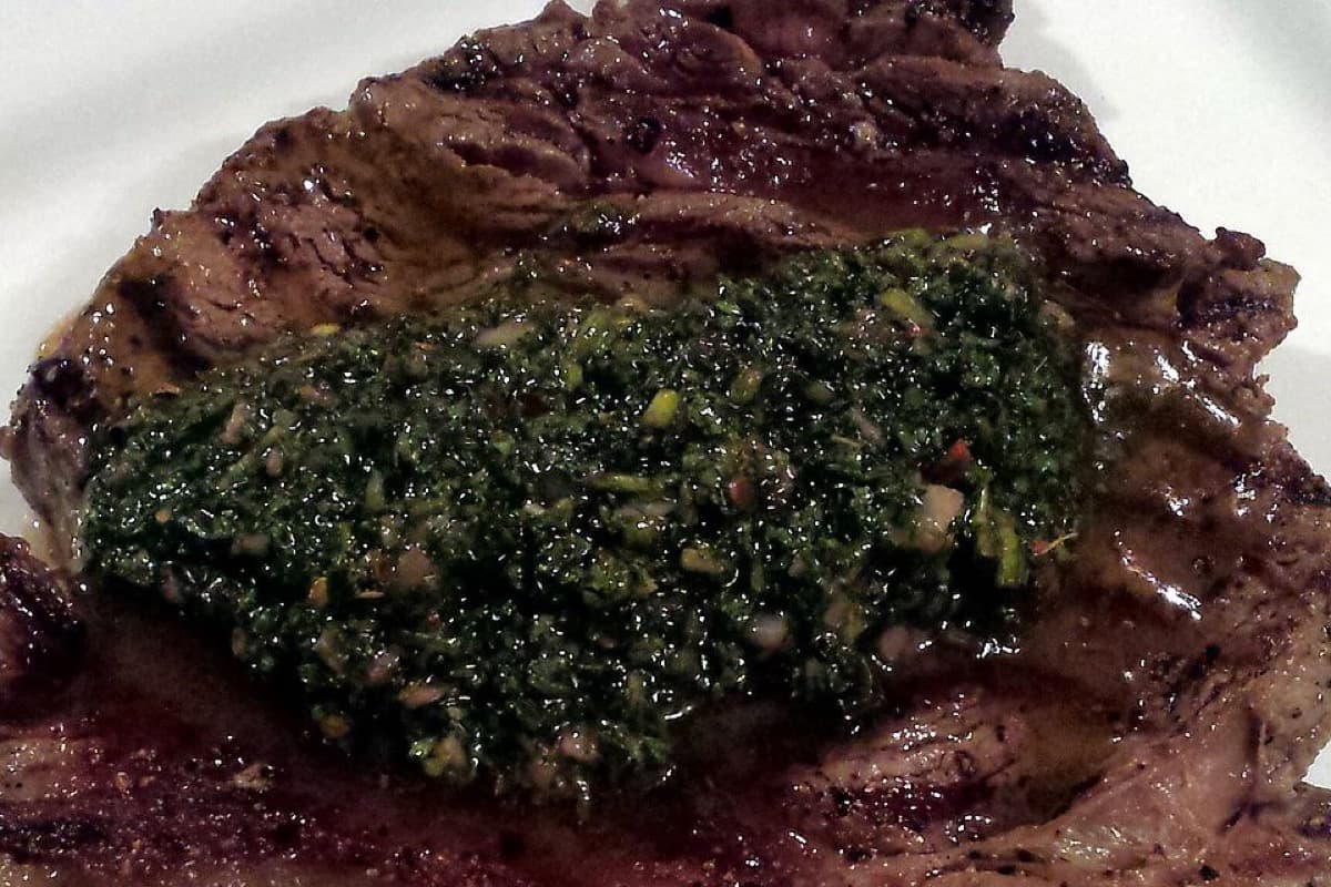 Grilled steak topped with green chimichurri sauce