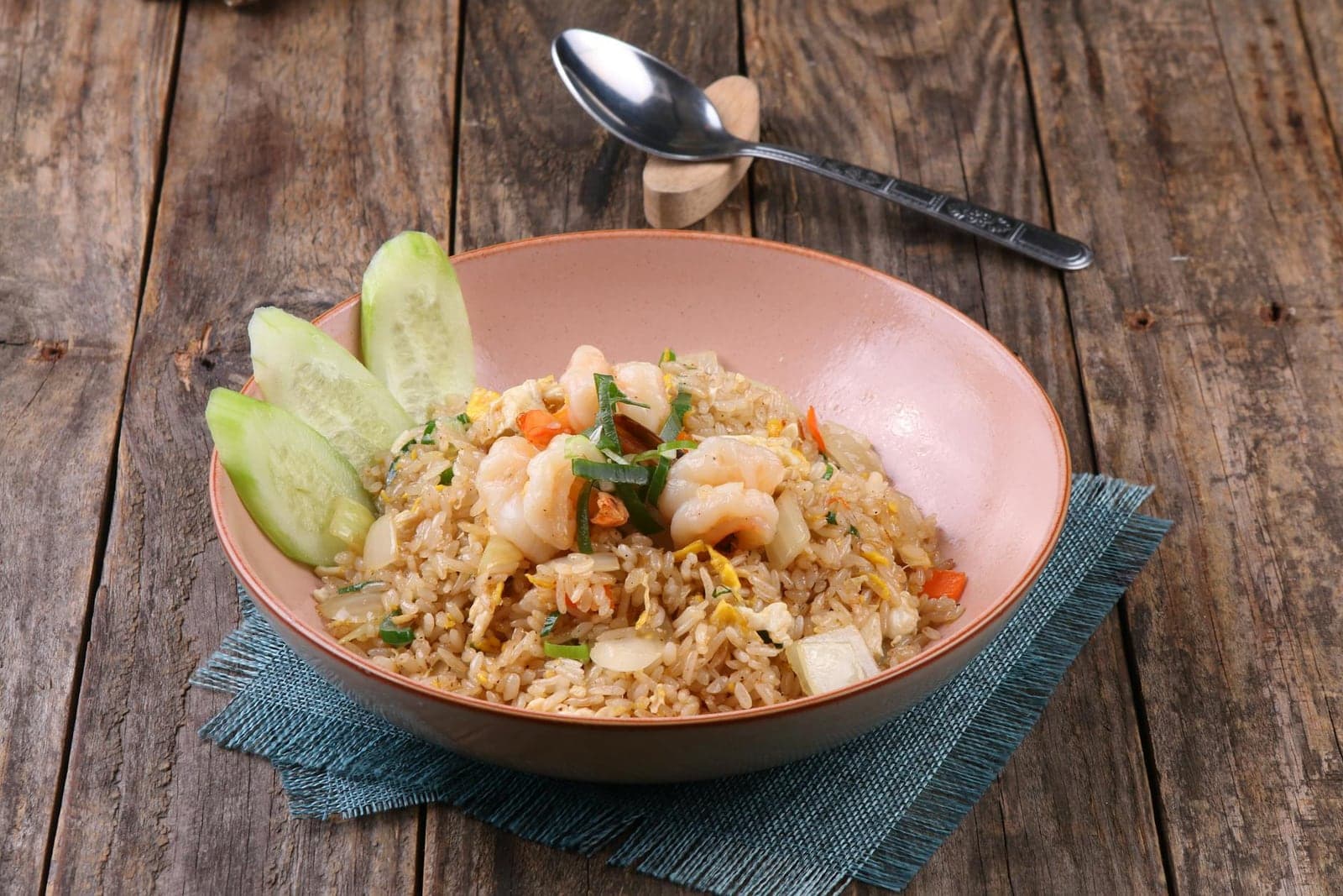 Family-style fried rice bowl with shrimp, cucumber, and vegetables on a wooden table
