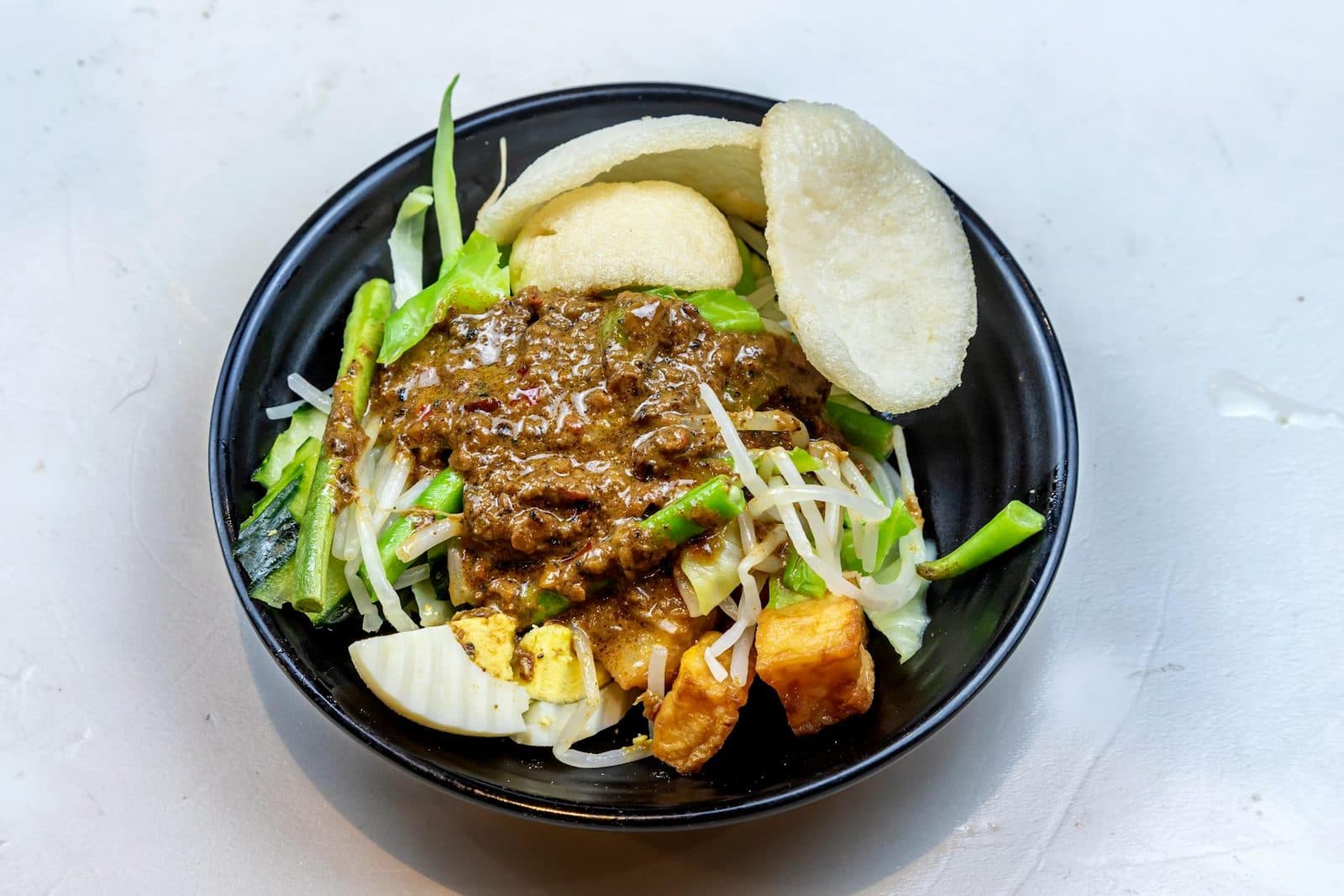Indonesian gado gado salad bowl with vegetables, tofu, peanut sauce, and crisp garnish