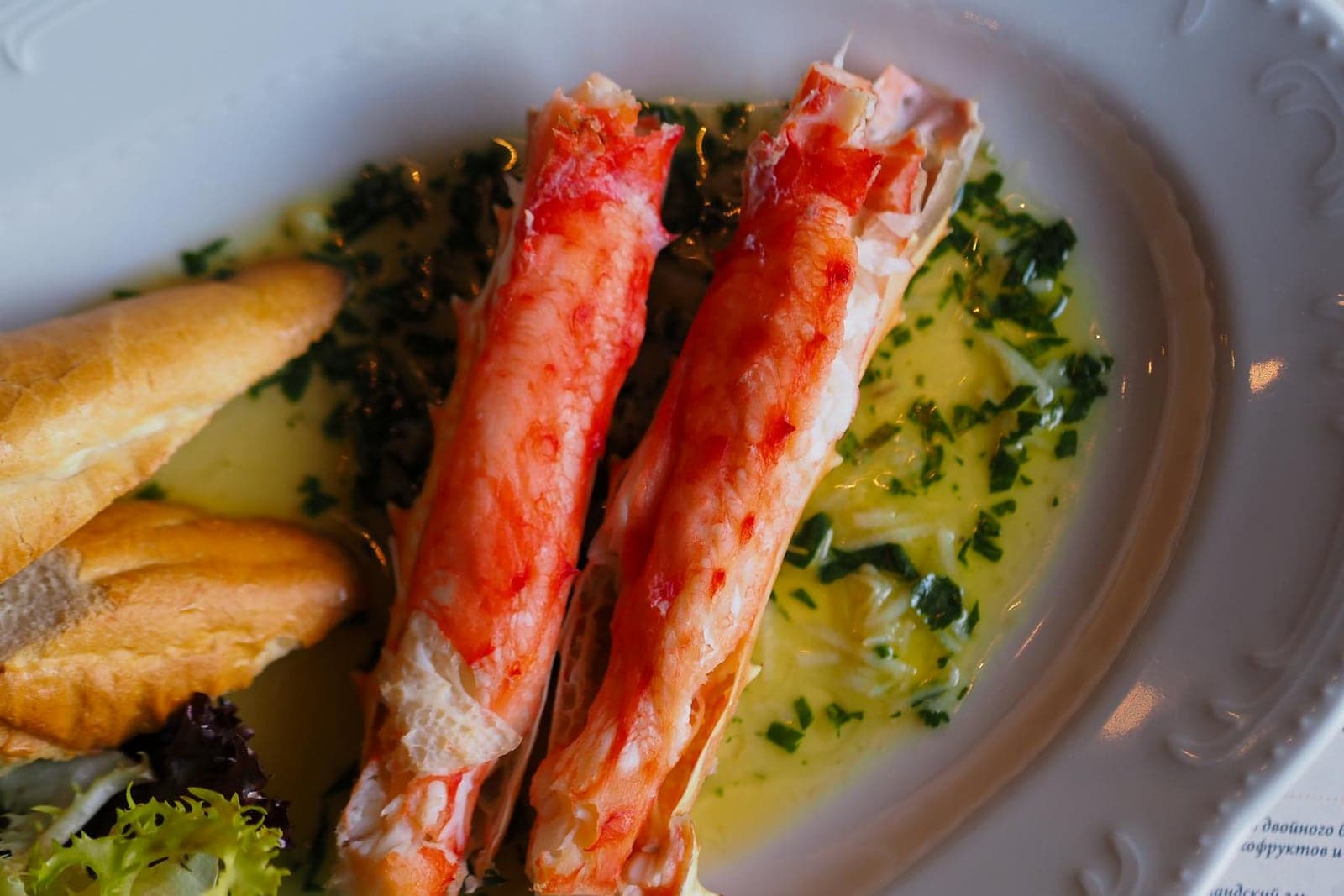 Garlic butter crab legs served with herbs and sauce in a shallow dish