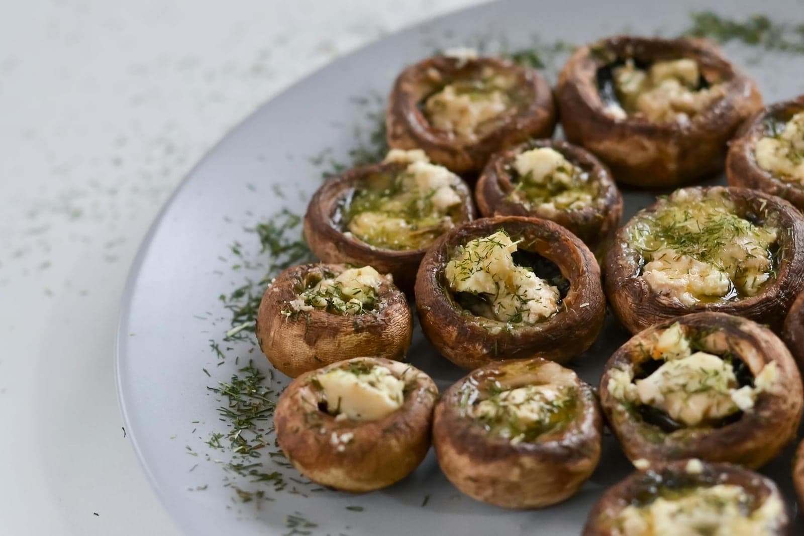 Garlic herb stuffed mushrooms with cream cheese filling and herbs on a white plate