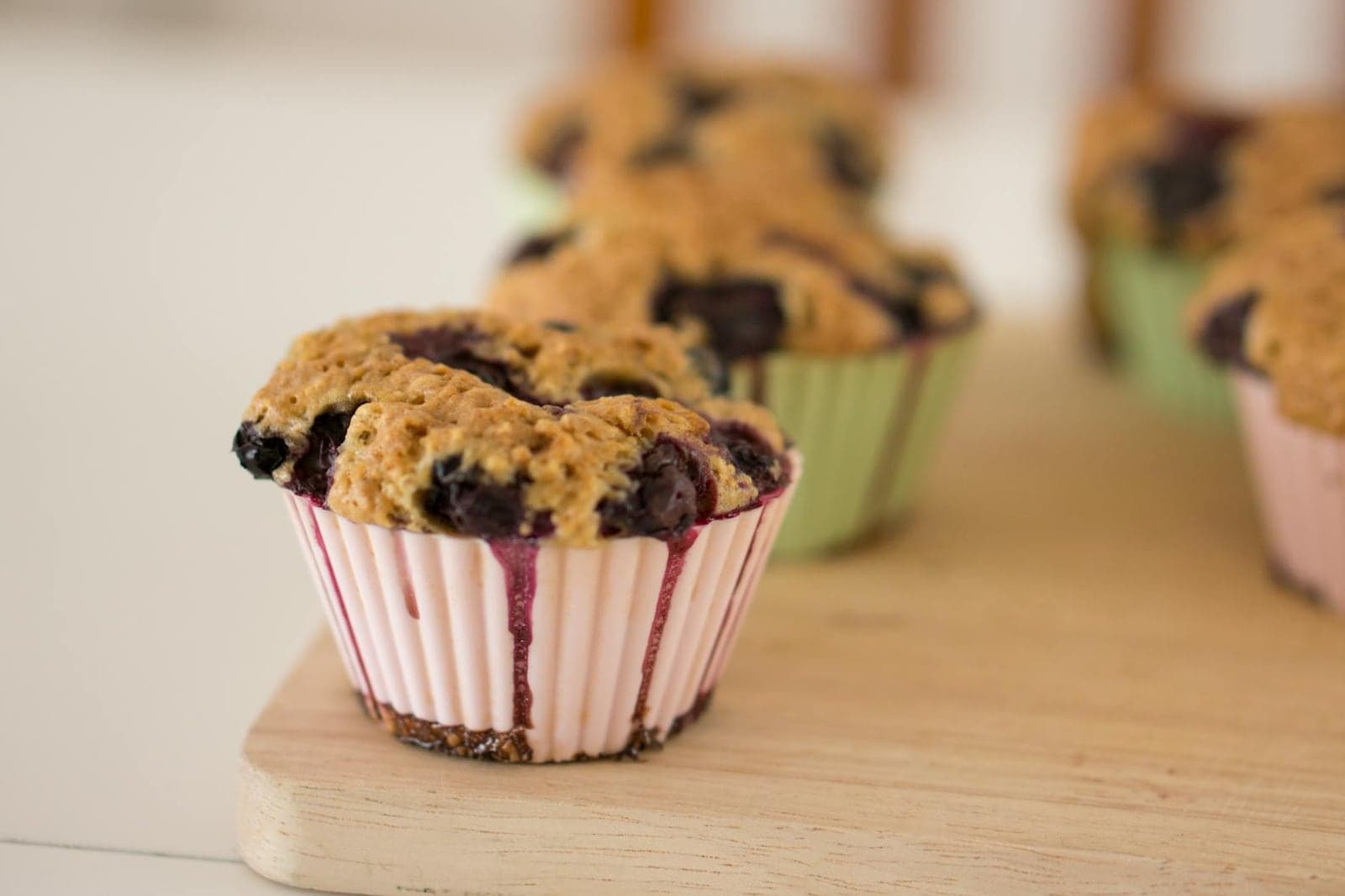 Gluten-free blueberry muffin-style muffins baked in paper cups on a wooden board