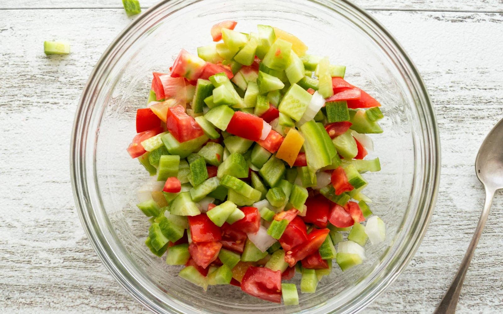 Israeli chopped salad with cucumber, tomato, and peppers in a glass bowl