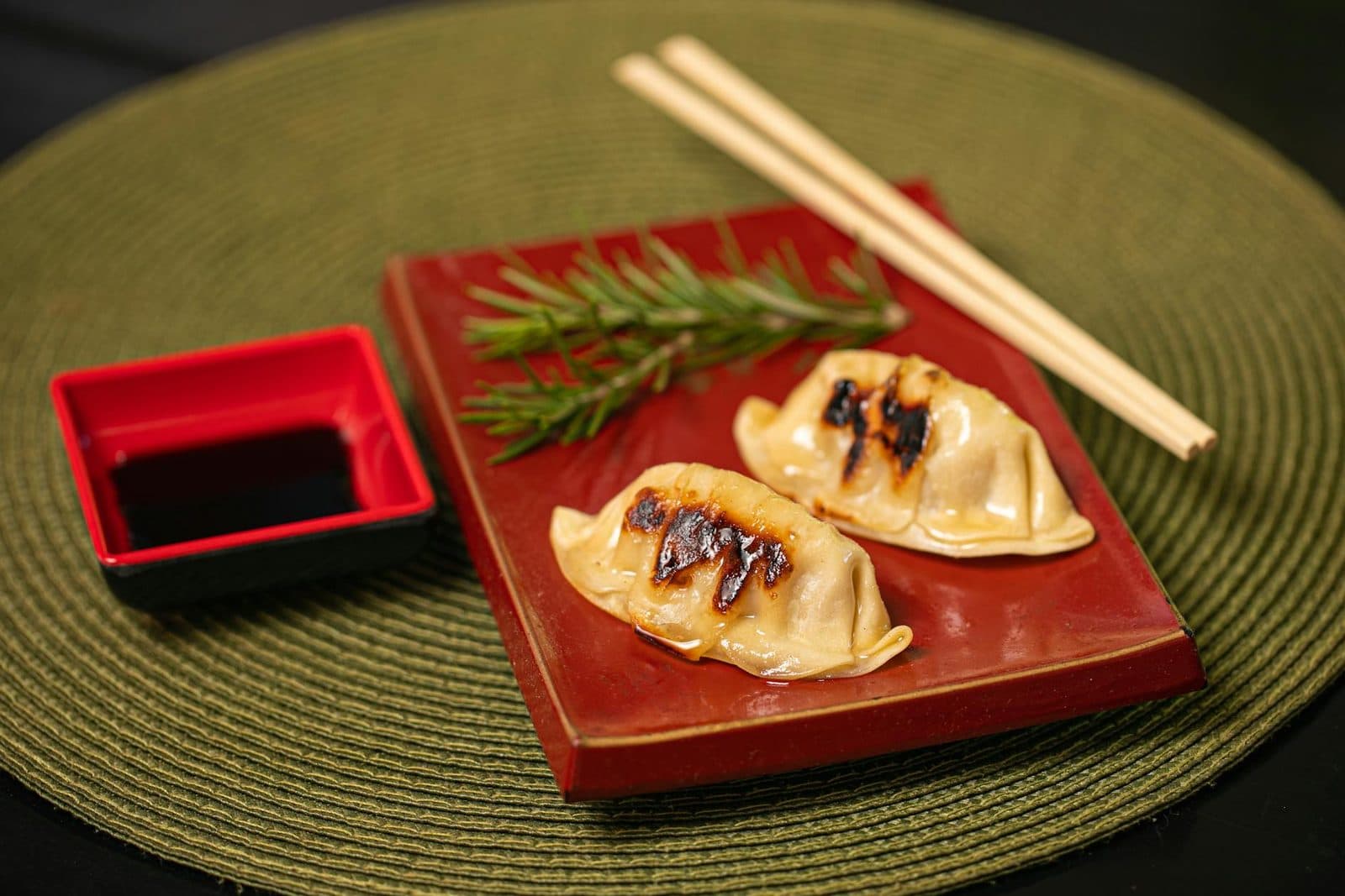 Japanese gyoza dumplings on a red plate with soy dipping sauce