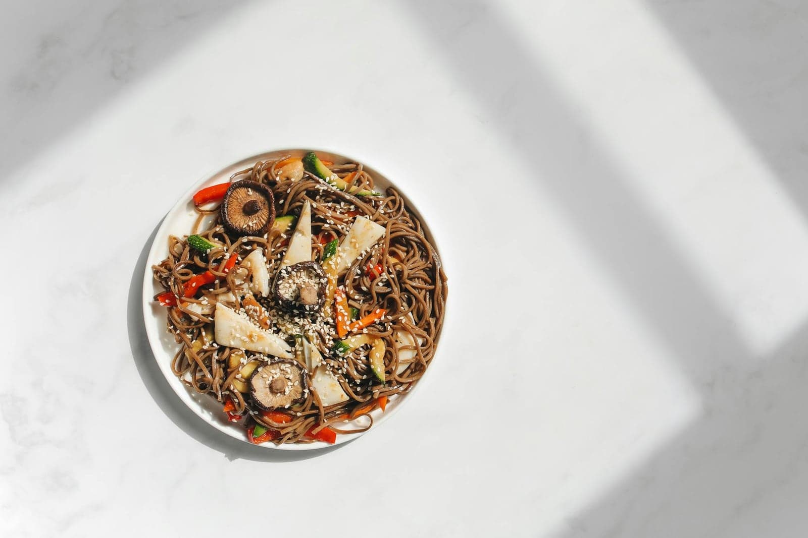 Japanese sesame tofu soba salad with noodles, vegetables, mushrooms, and sesame garnish