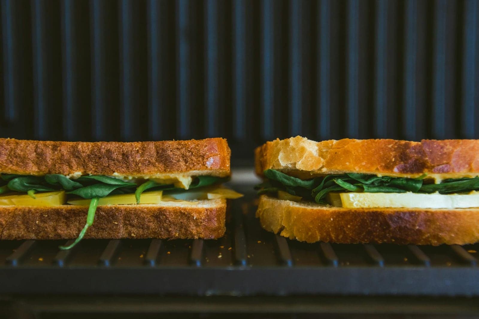 Kimchi grilled cheese sandwiches toasting on a grill with browned bread and green filling