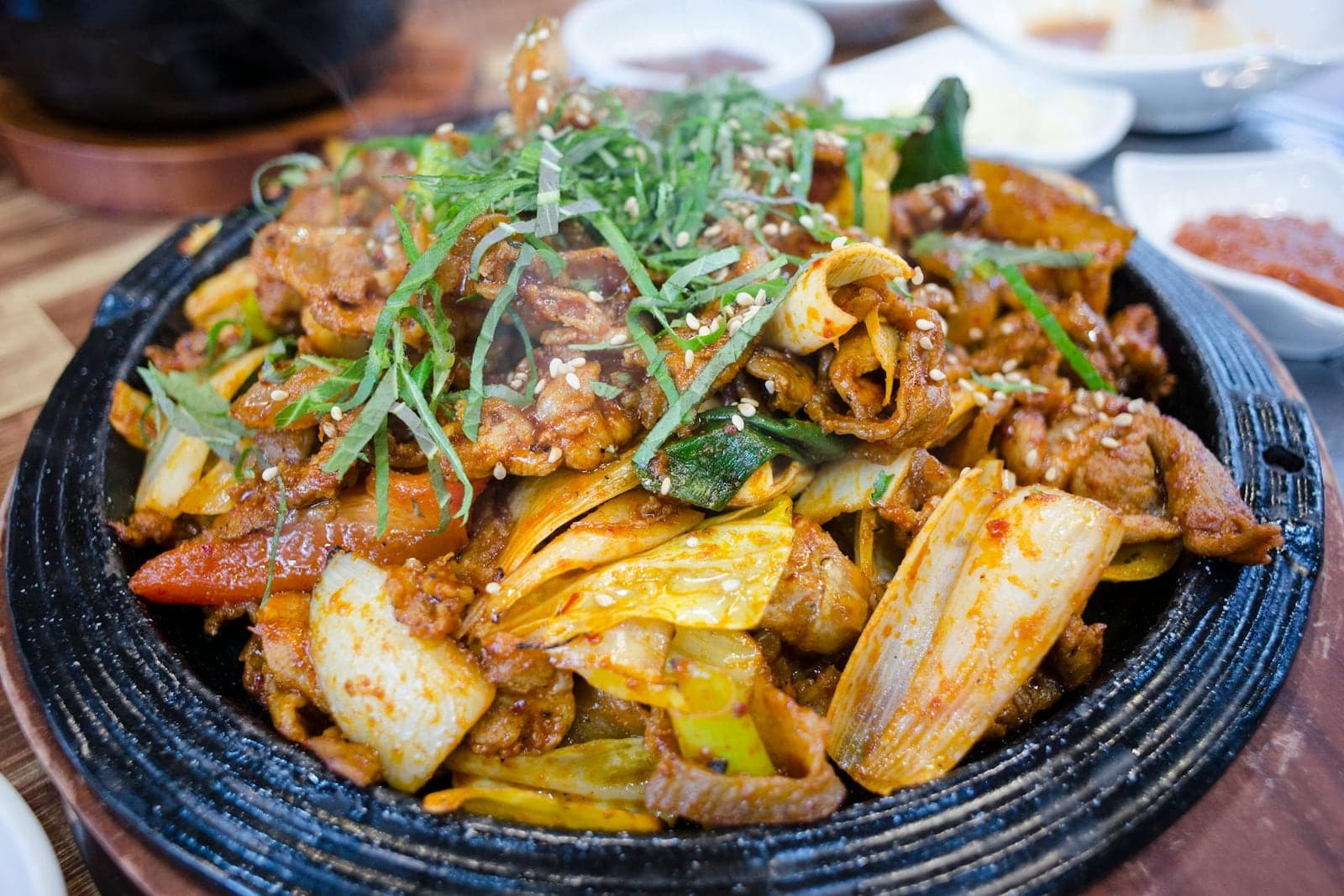 Korean spicy pork with cabbage and scallions on a sizzling plate
