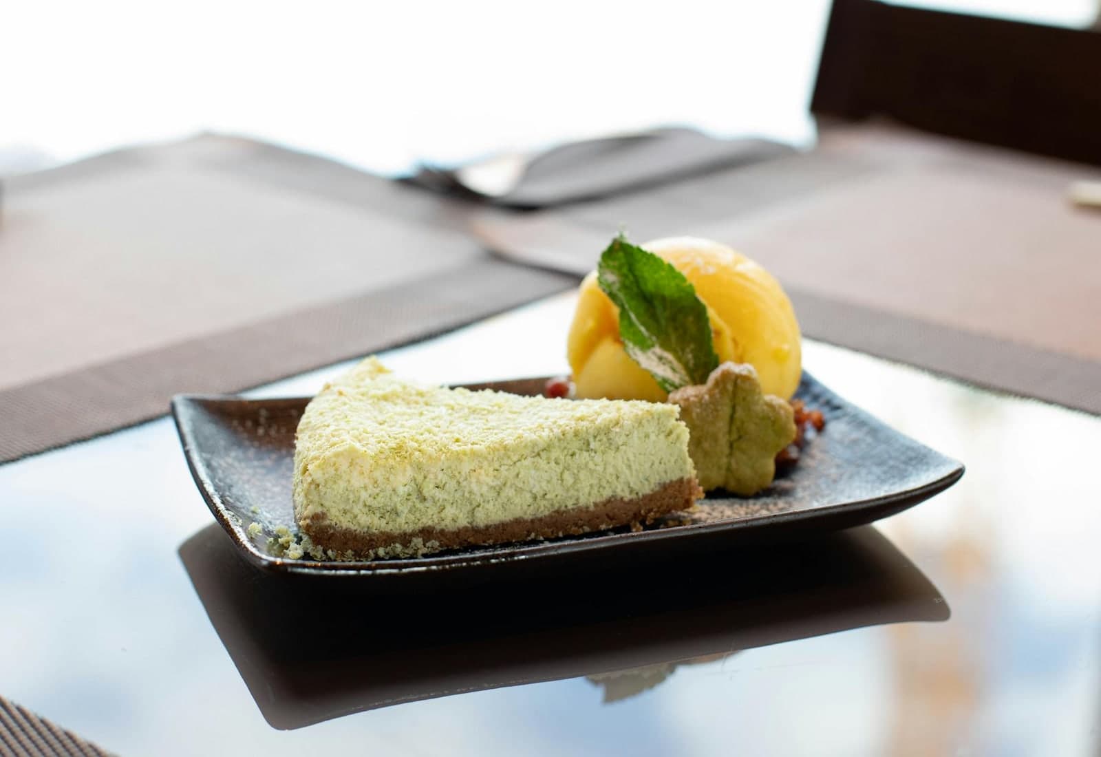 Matcha cheesecake slice served with mango sorbet and mint garnish on a plate