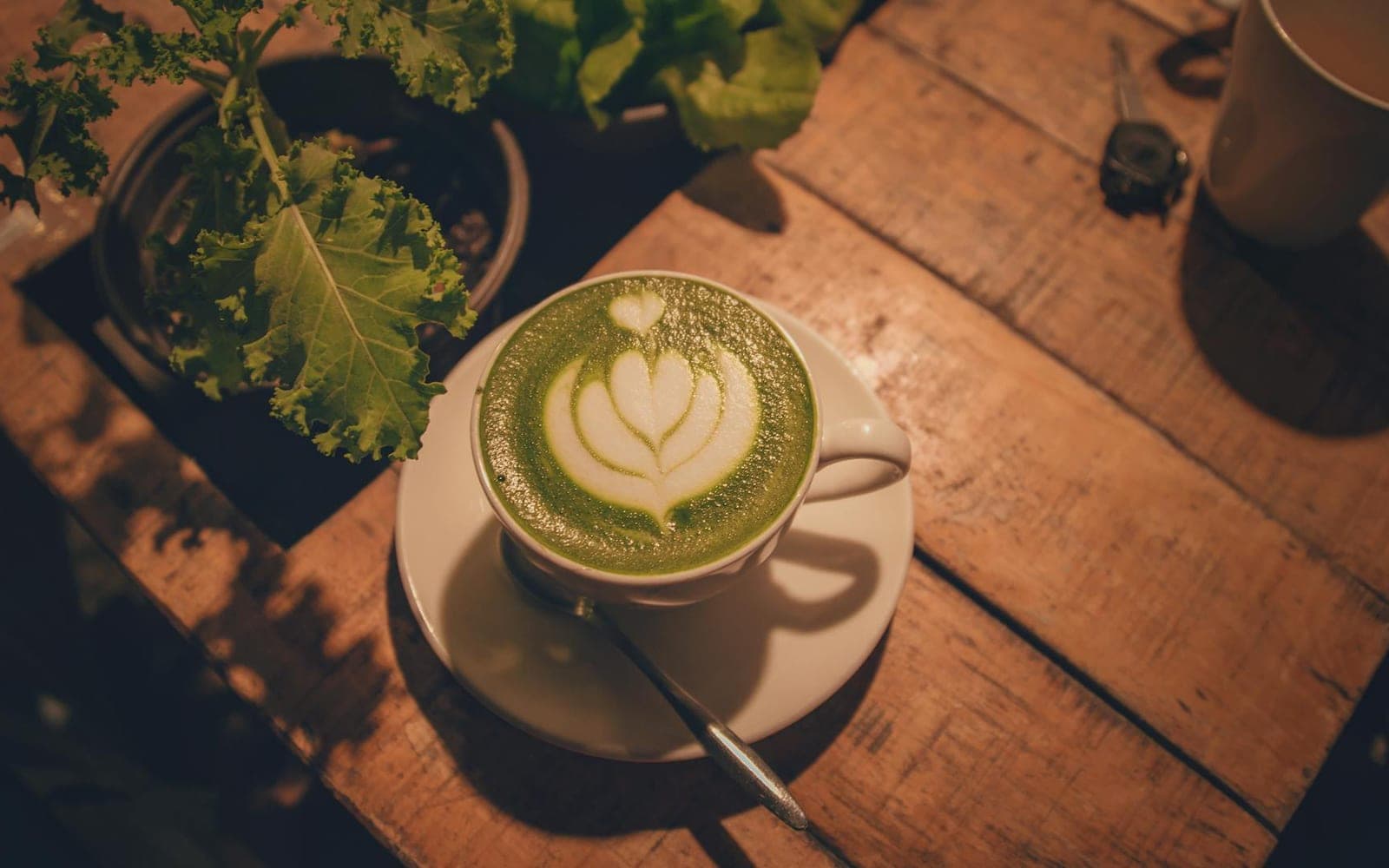 Matcha latte in a white cup with green tea foam on a wooden table