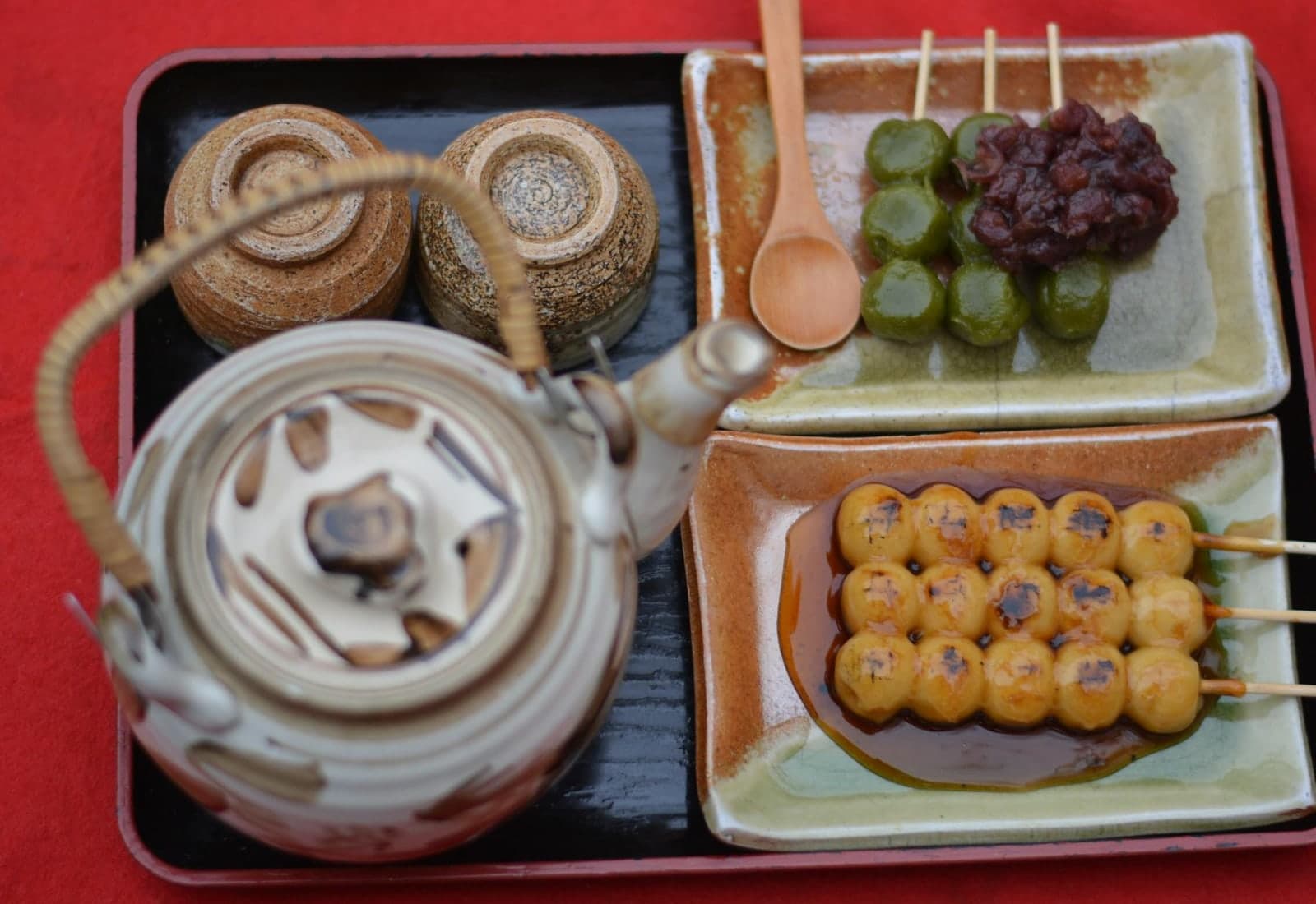 Mitarashi dango Japanese rice dumpling skewers served with tea on a red tray