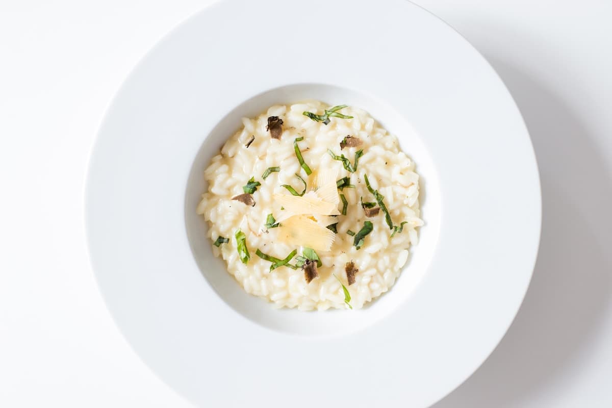 Bowl of creamy mushroom risotto garnished with fresh thyme and shaved Parmesan cheese