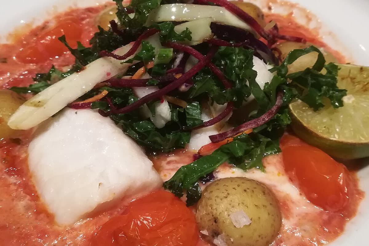White cod fillet in tomato sauce with greens and potatoes
