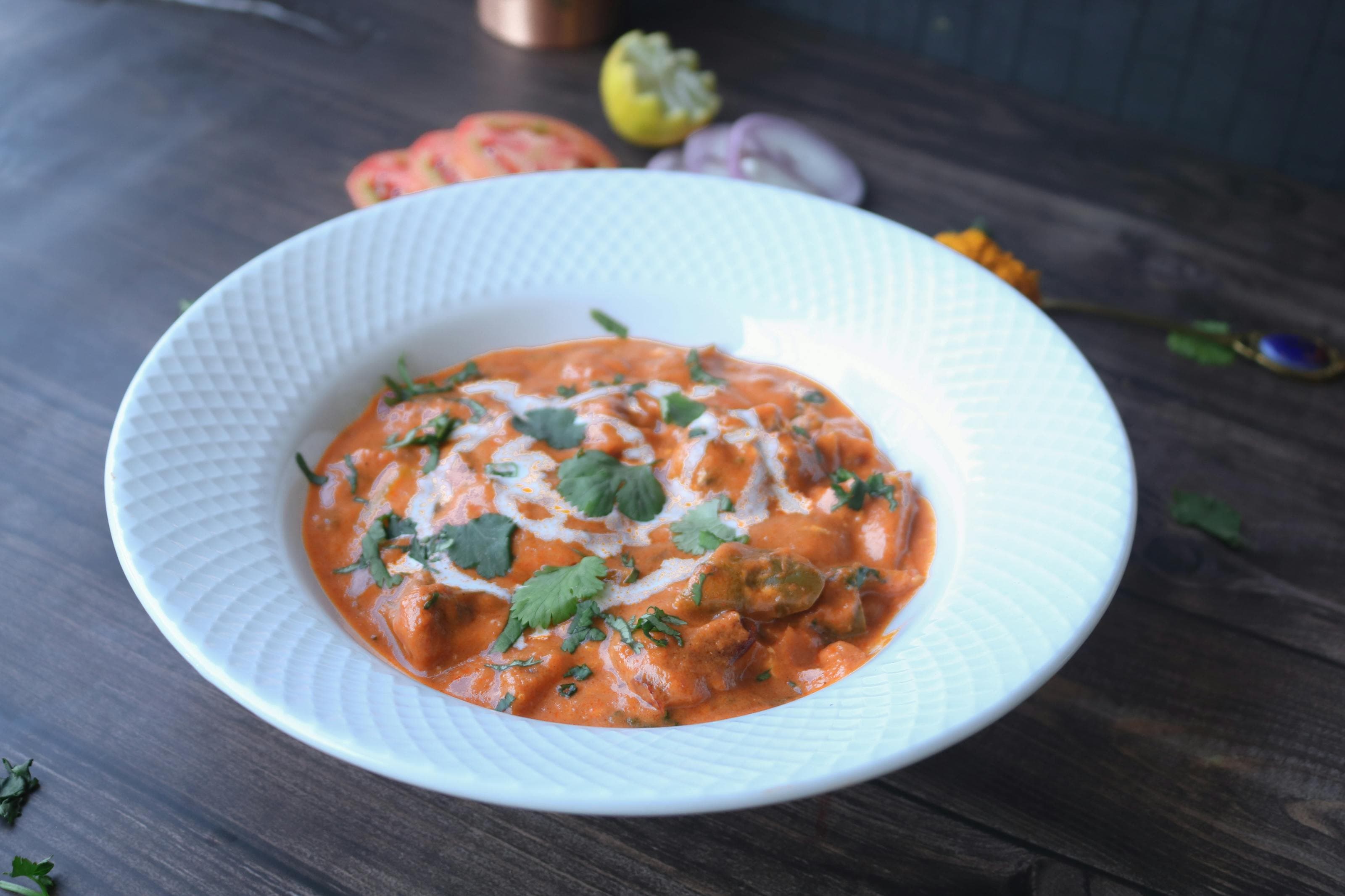 Paneer butter masala in creamy tomato sauce with cilantro in a white bowl