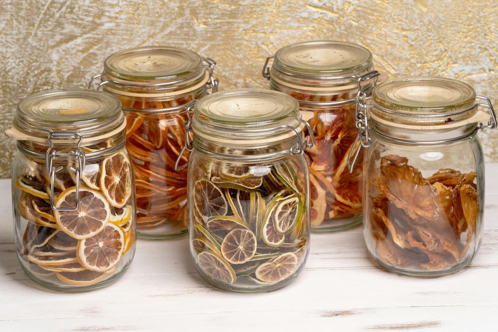 Preserved lemons and citrus slices packed in glass jars on a white table