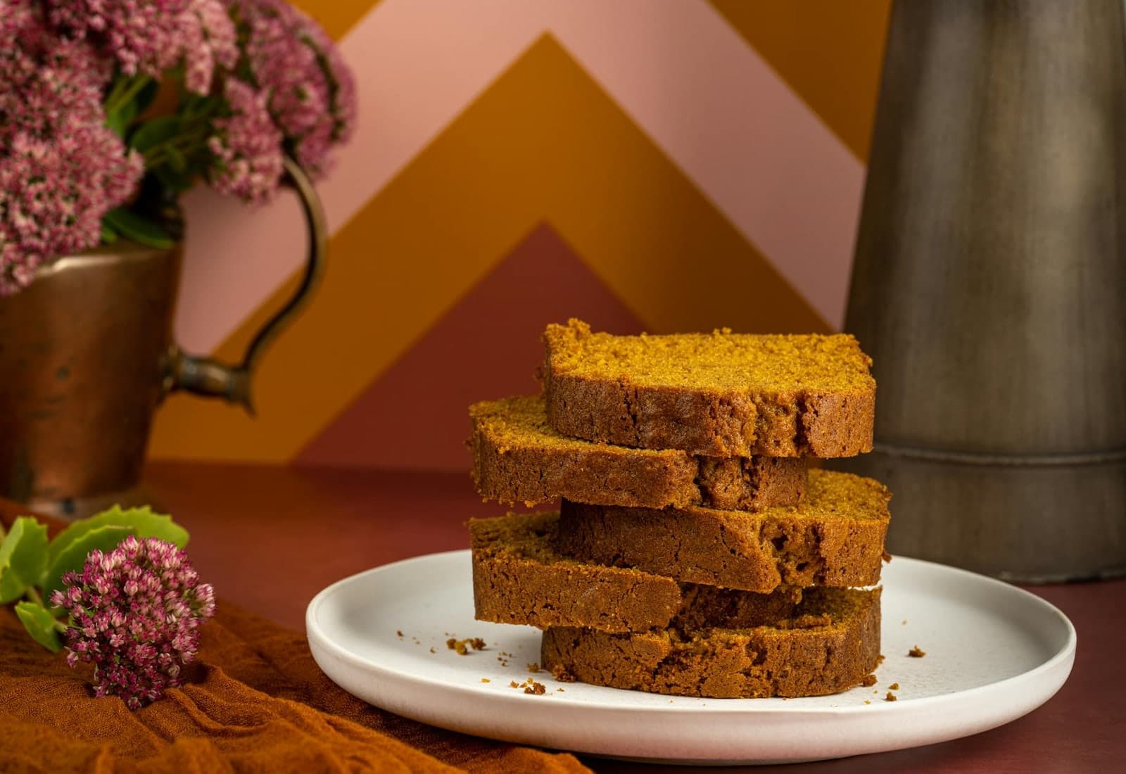Pumpkin bread loaf slices stacked on a plate with a cozy fall backdrop