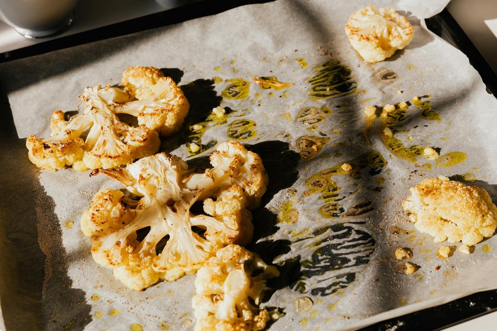 Roasted cauliflower steaks browned on parchment with herbs and olive oil