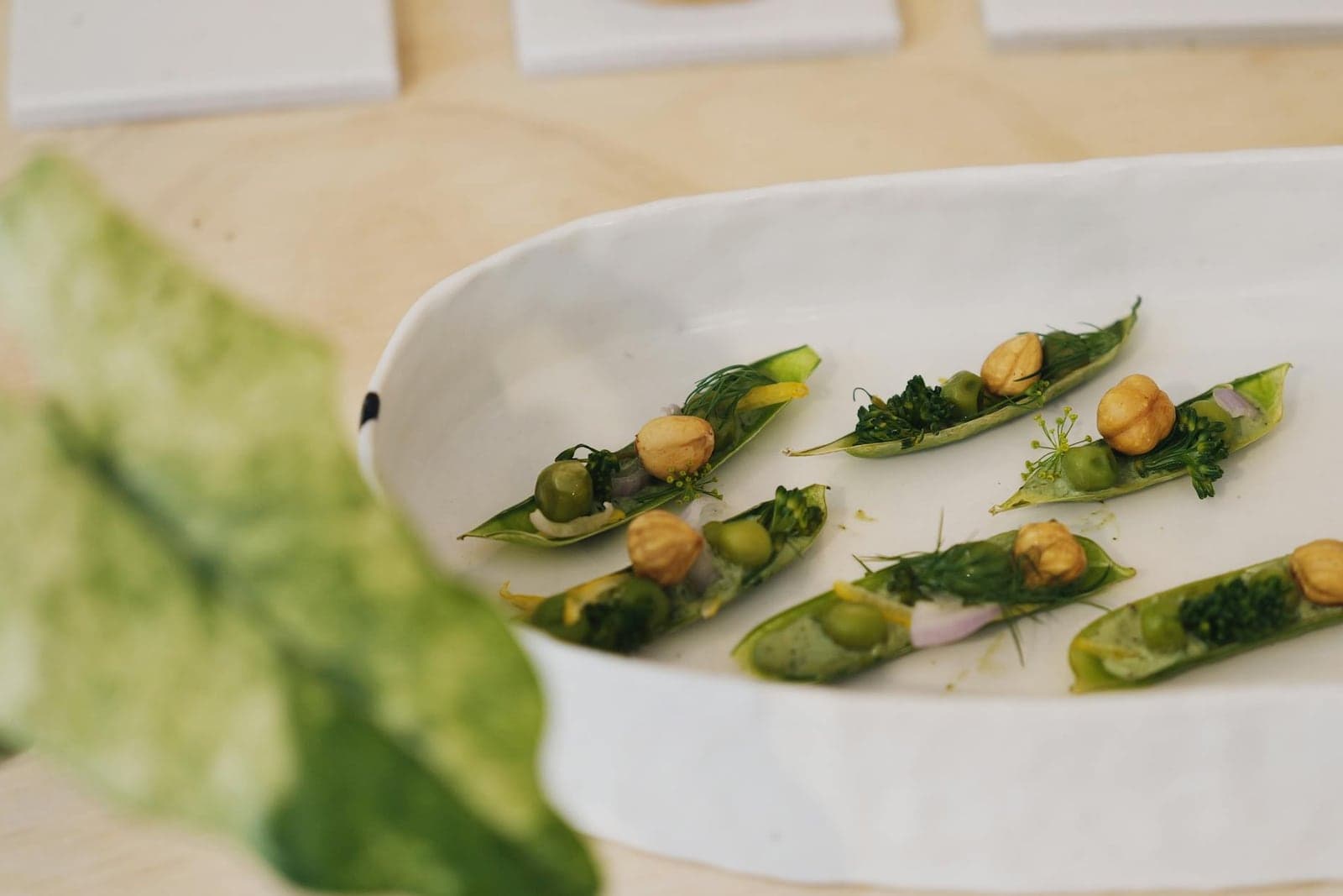 Spring pea ricotta crostini-style bites with peas, greens, and toasted toppings on a white platter