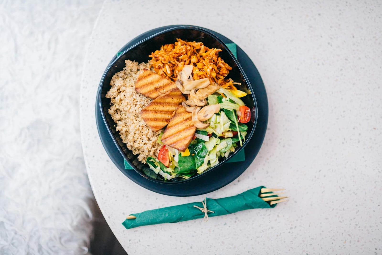 Teriyaki tofu bowl with grains, vegetables, shredded carrots, greens, and sliced tofu