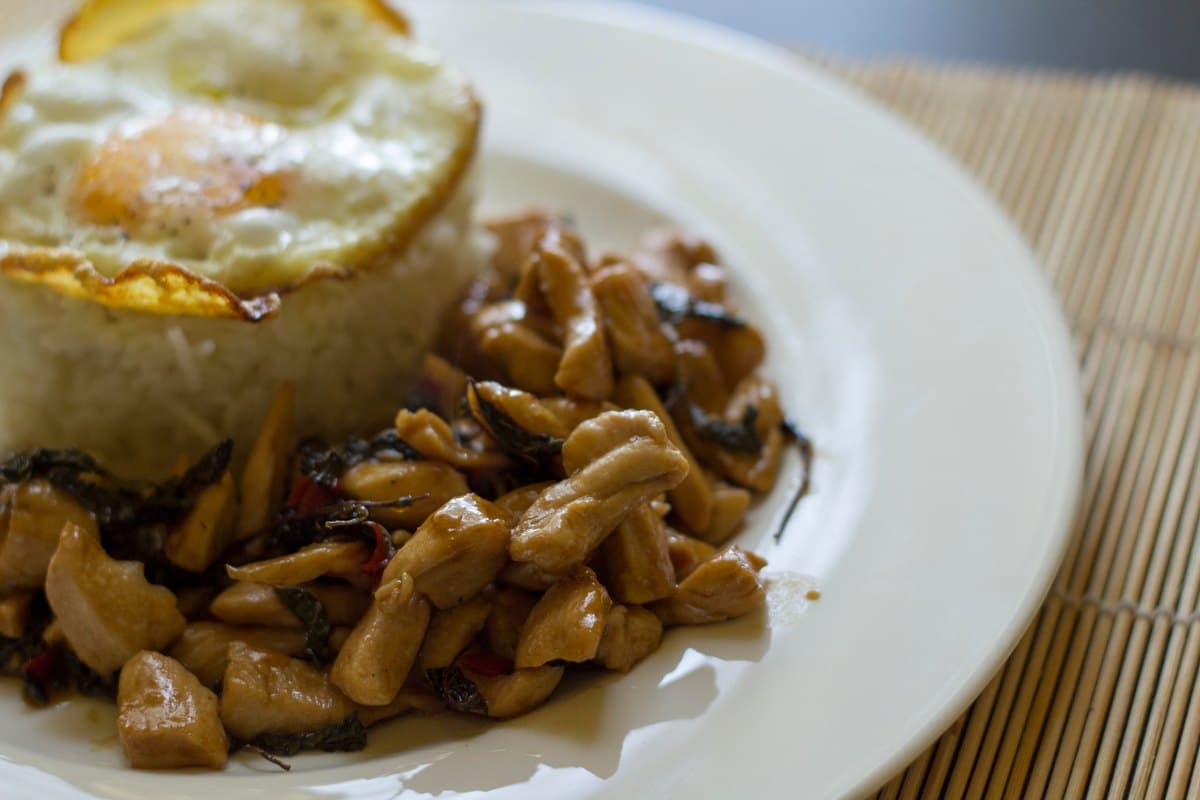 Thai basil chicken stir fry served over rice with a fried egg