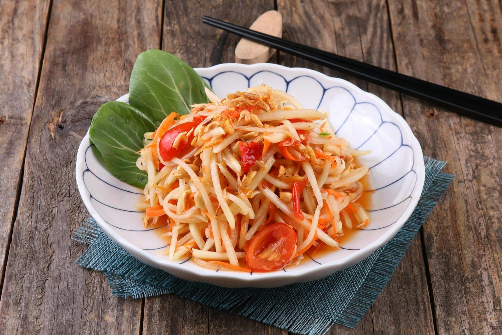Thai green papaya-inspired slaw with tomato, lime, and shredded vegetables in a white bowl