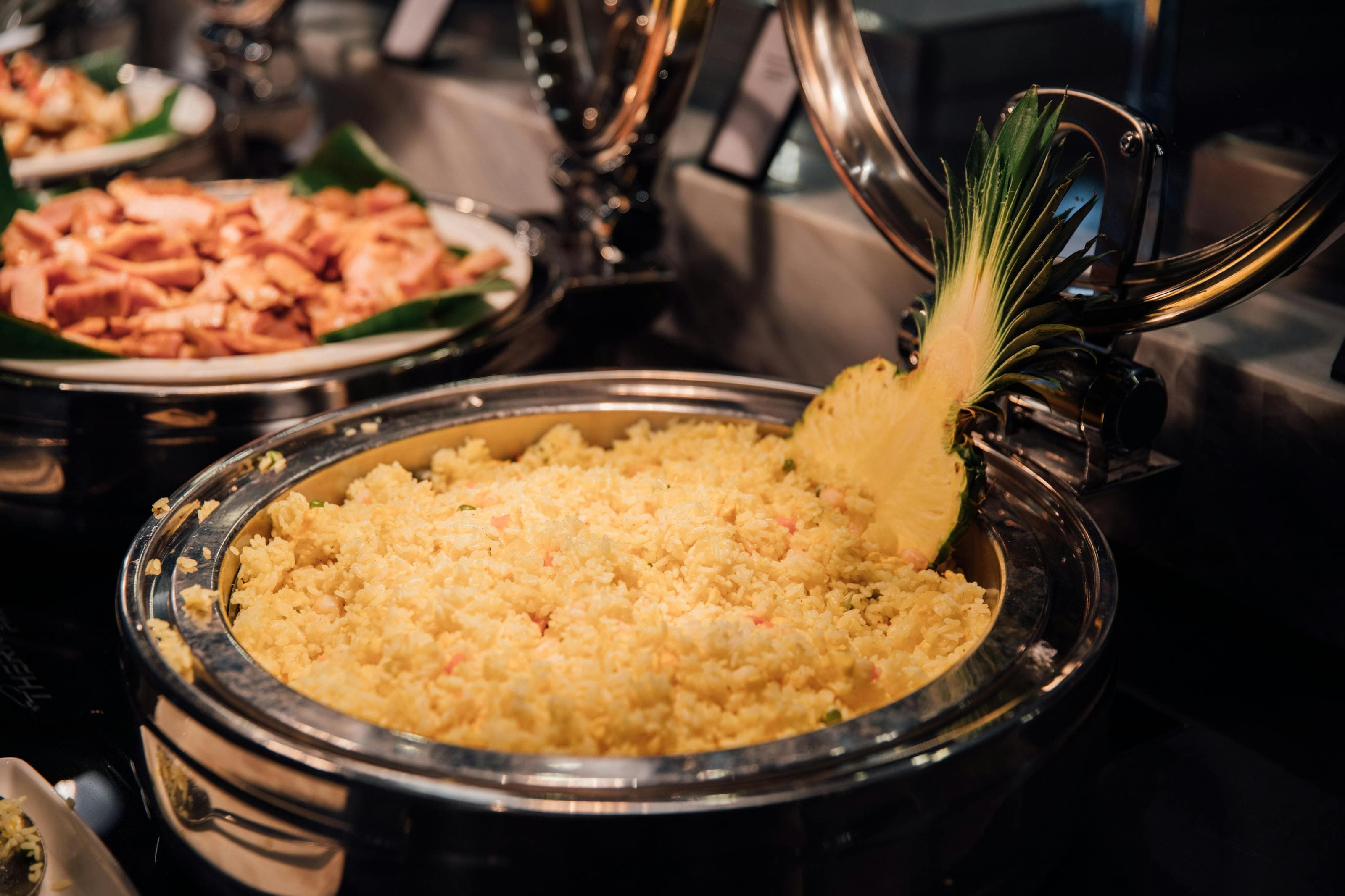 Thai pineapple fried rice with yellow rice and pineapple garnish in a buffet pan