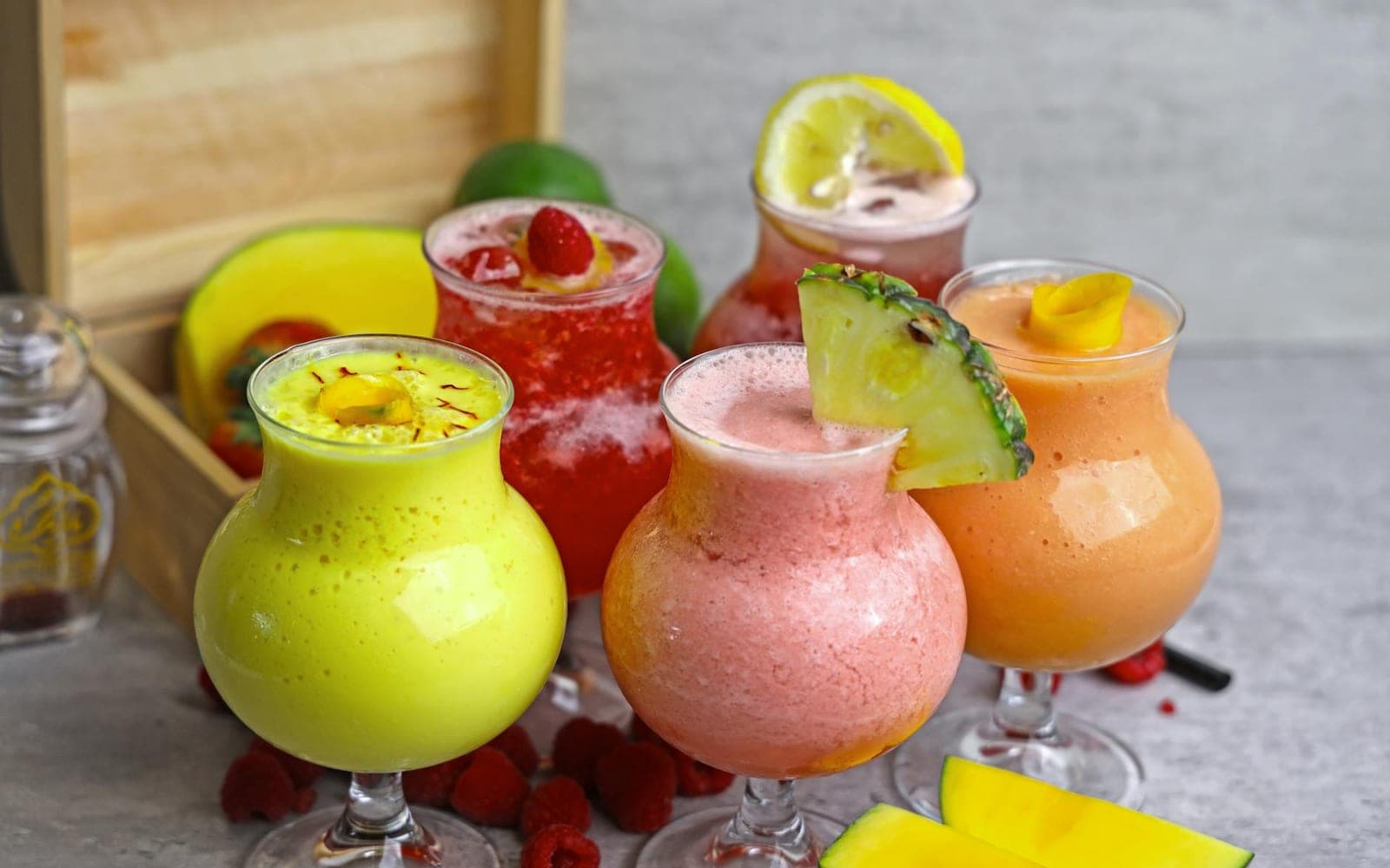 Tropical smoothie glasses in bright colors with fresh fruit garnishes