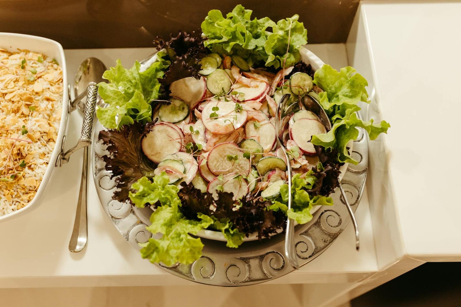 Watermelon radish salad with leafy greens, cucumbers, and radish slices on a platter