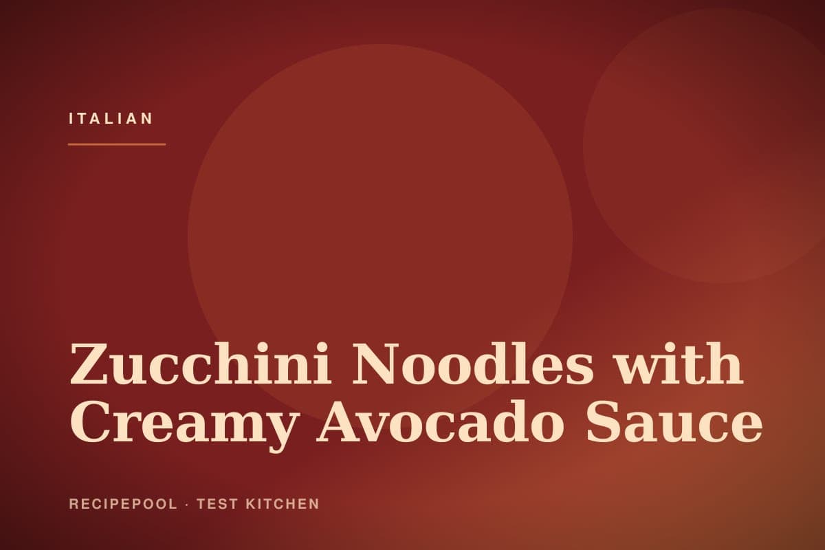 Bowl of zucchini noodles tossed in creamy green avocado sauce with cherry tomatoes