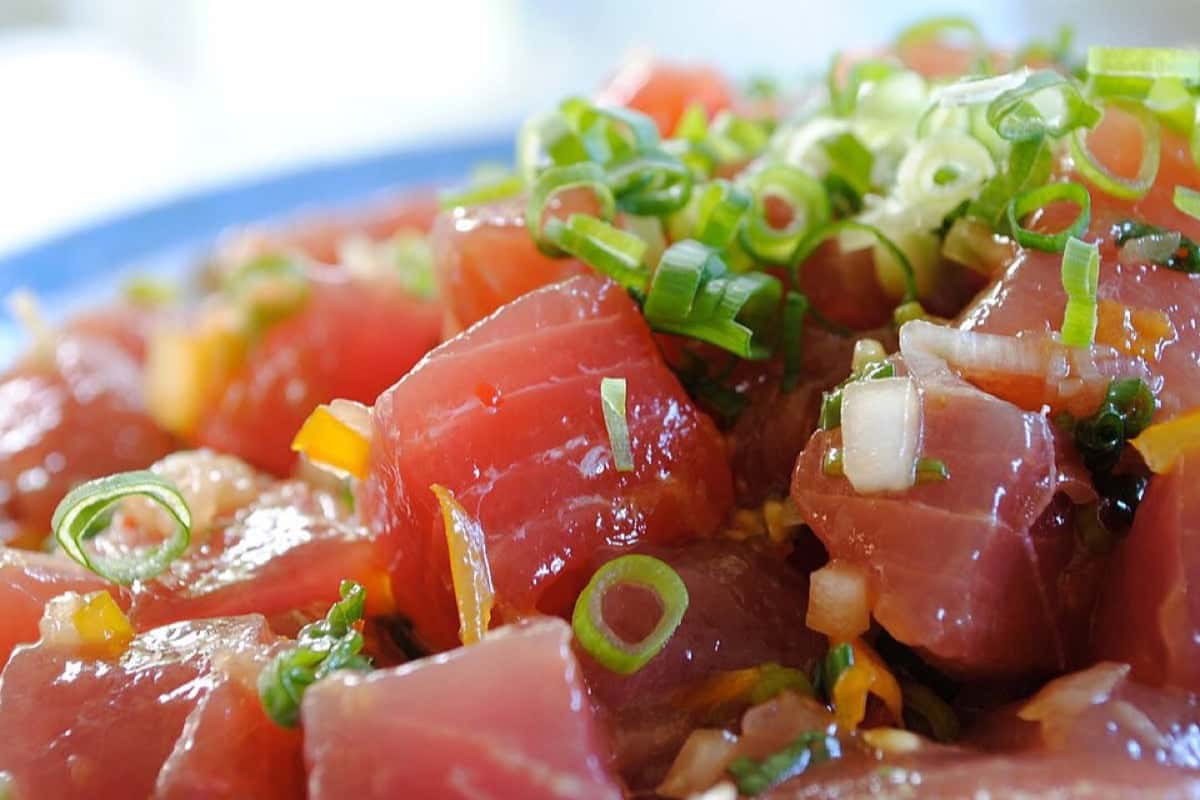 Ahi tuna poke bowl with glossy tuna cubes, scallions, and colorful vegetables