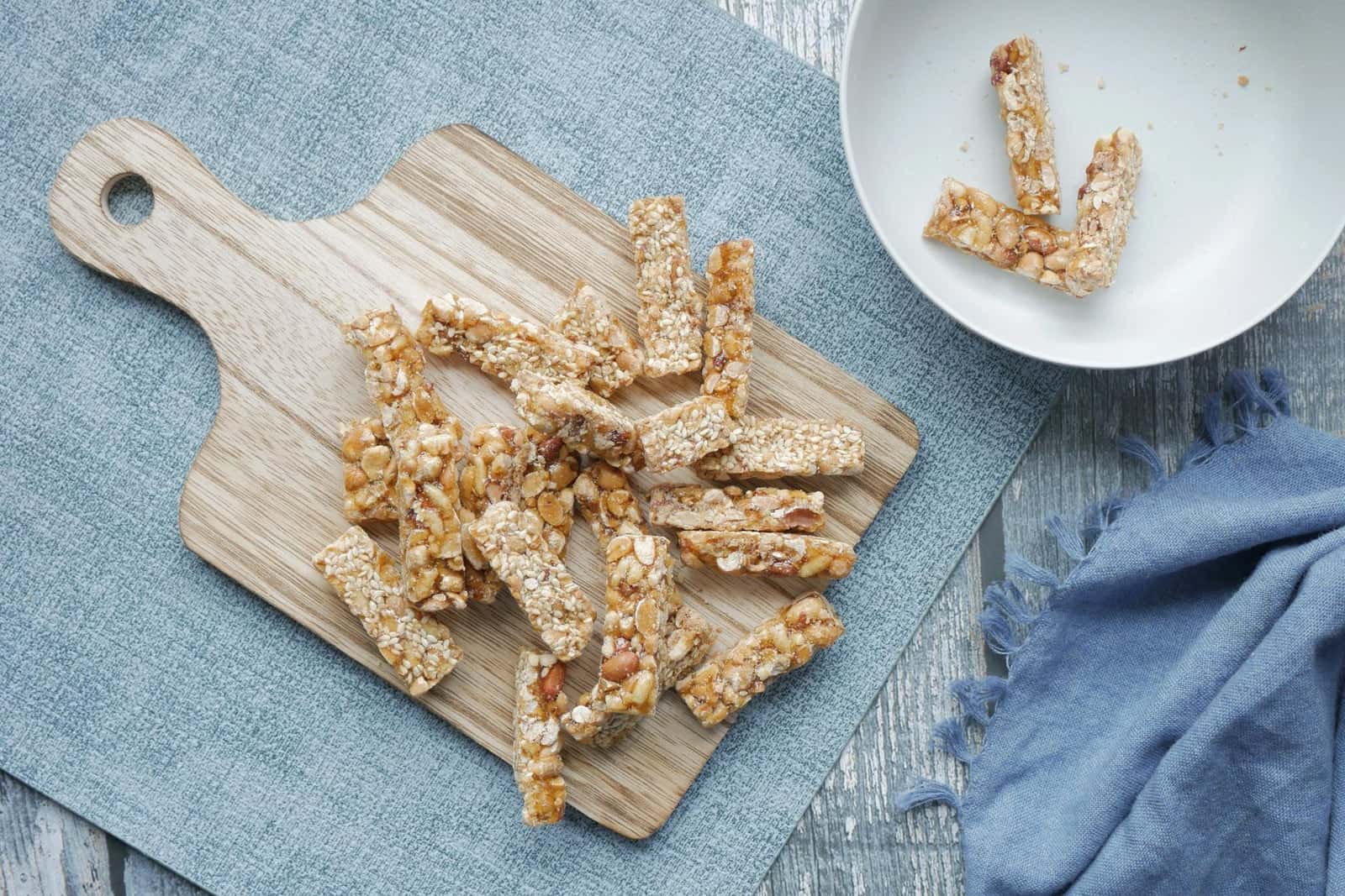 Peanut butter oat bars cut into sticks on a wooden board with a small white bowl