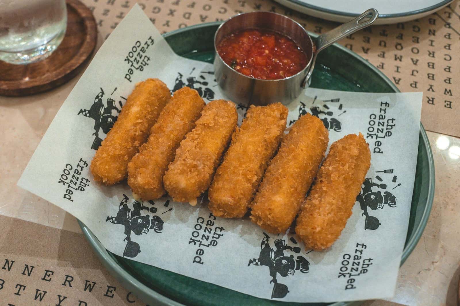 Baked mozzarella sticks with marinara dipping sauce on a restaurant plate