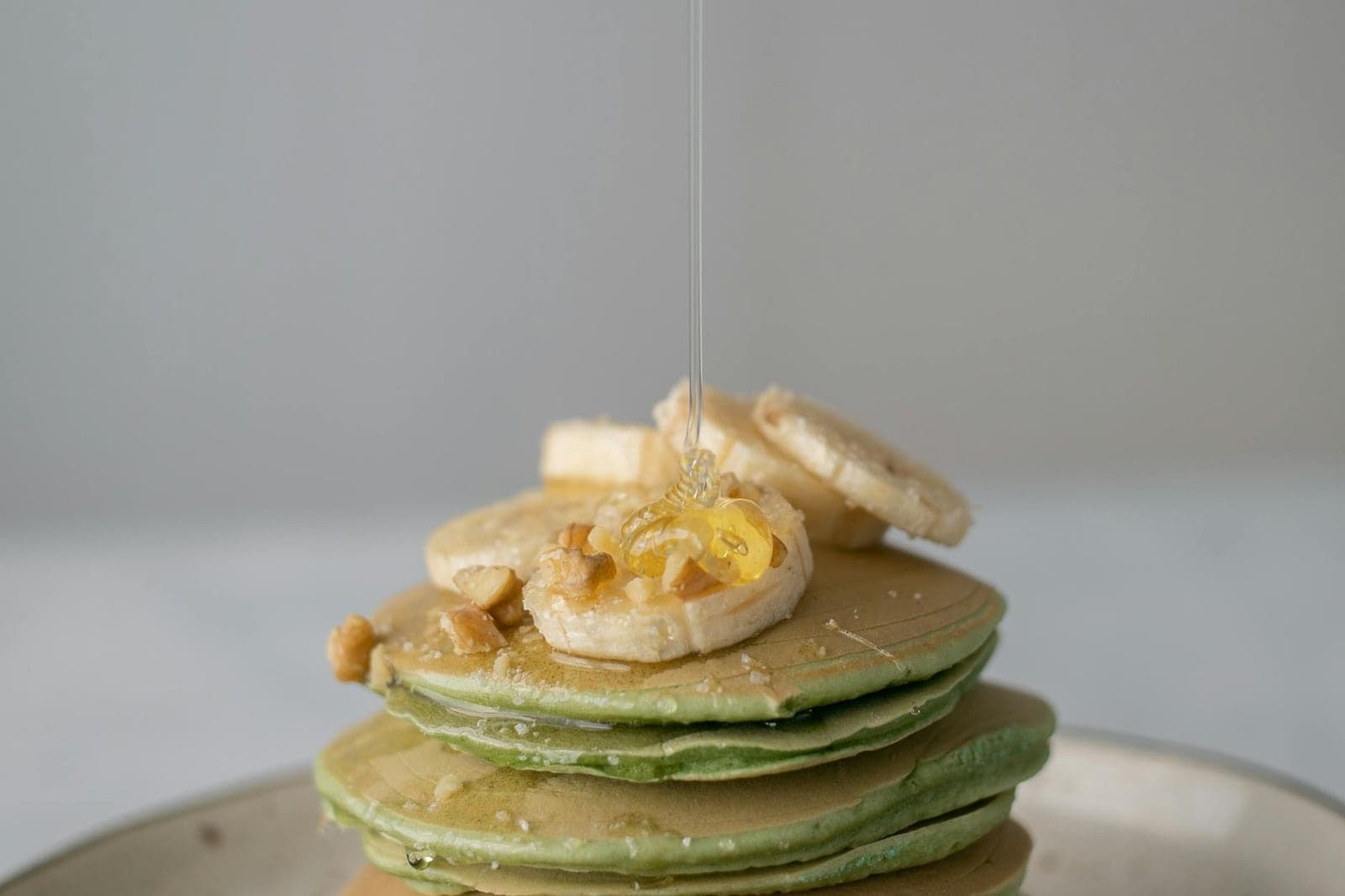 Banana protein pancakes stacked with banana slices and honey on a plate