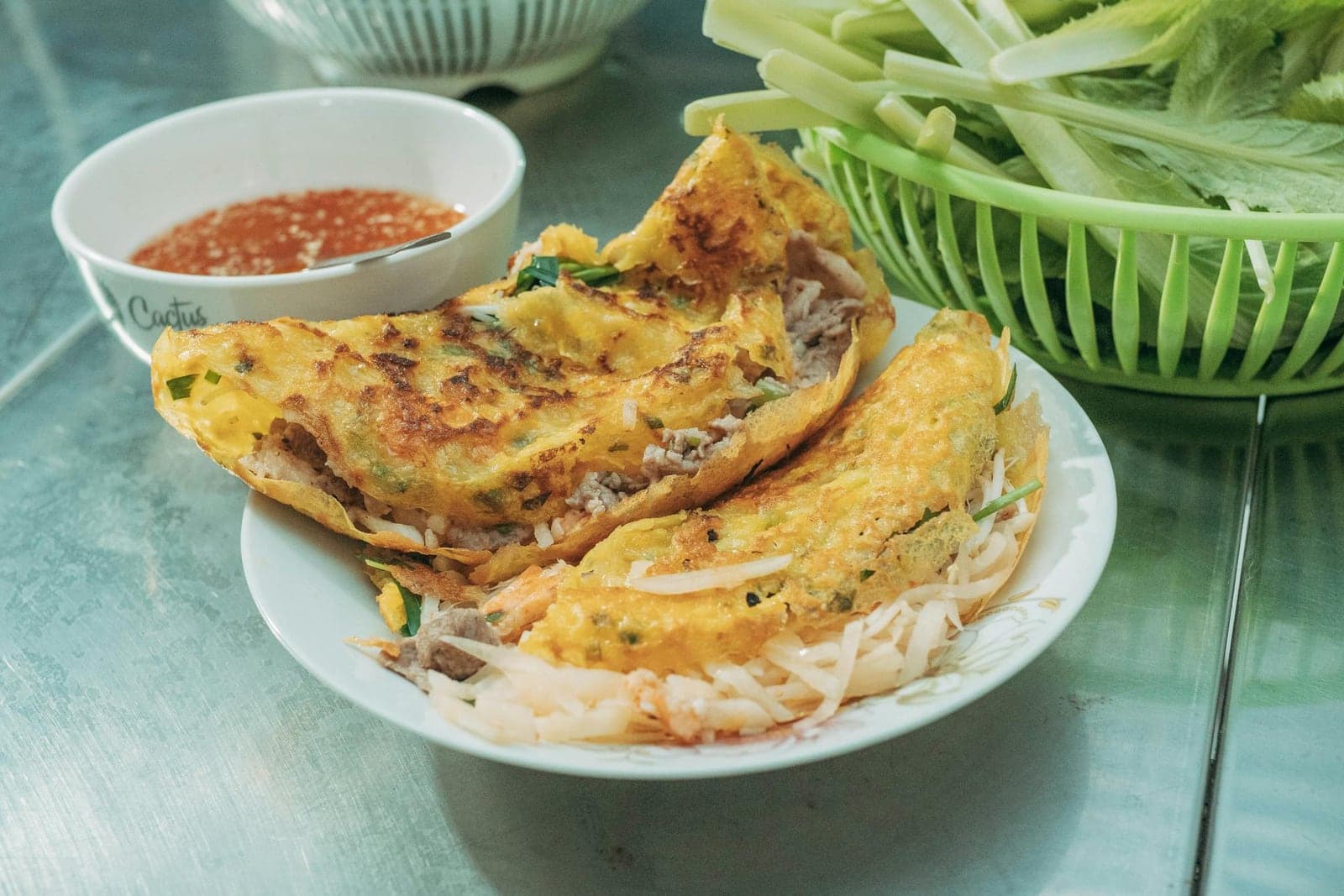 Banh xeo Vietnamese crepes folded with bean sprouts and served with herbs and dipping sauce