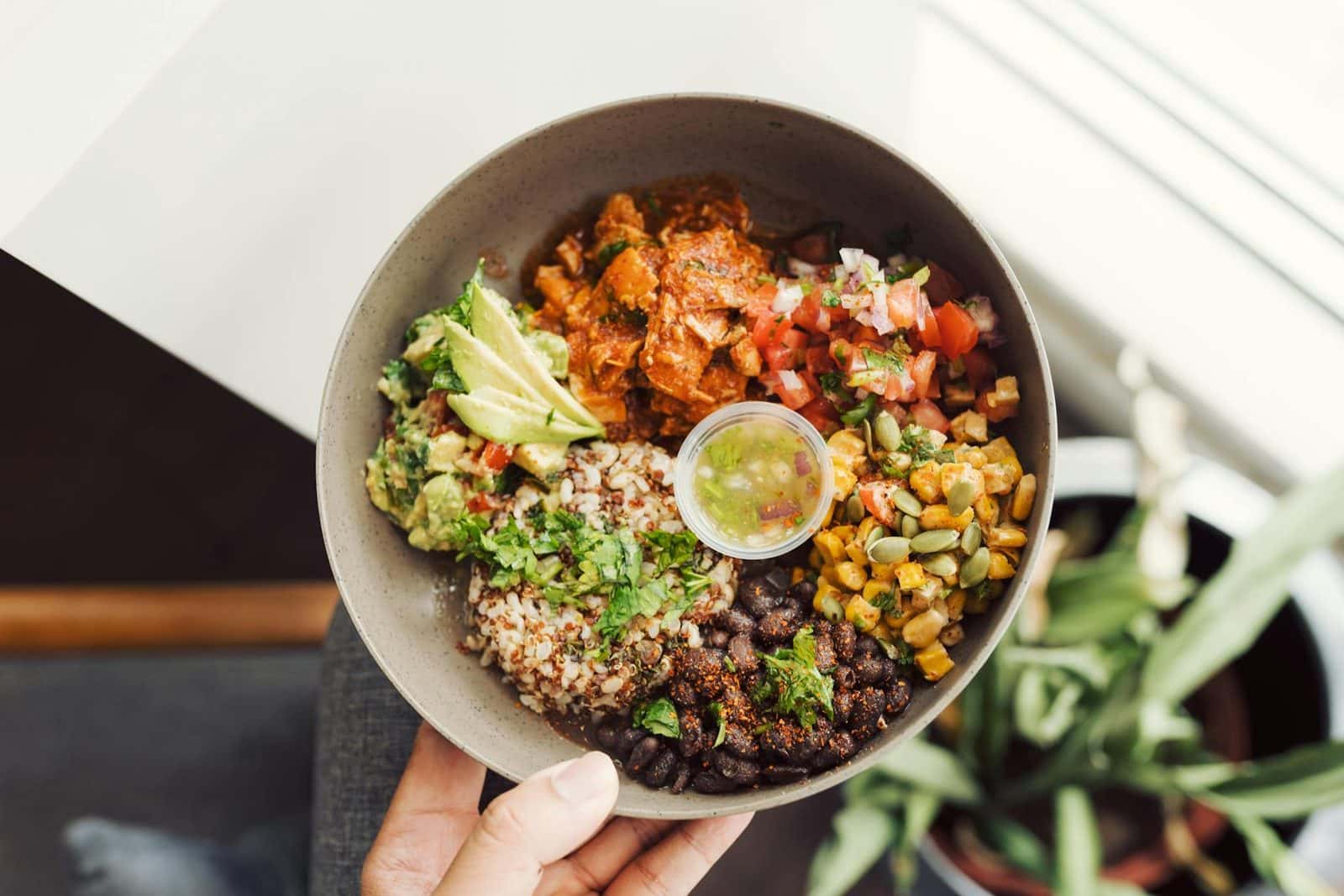 Black bean quinoa bowls with avocado, corn, salsa, lime, and fresh herbs