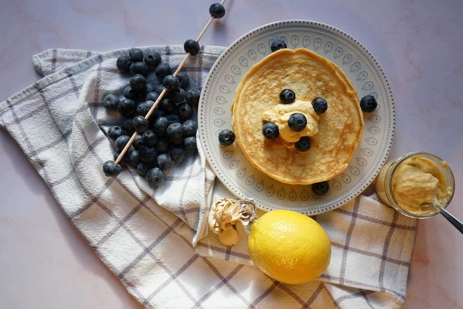 Lemon blueberry ricotta pancakes with blueberries, lemon, honey, and butter on a table
