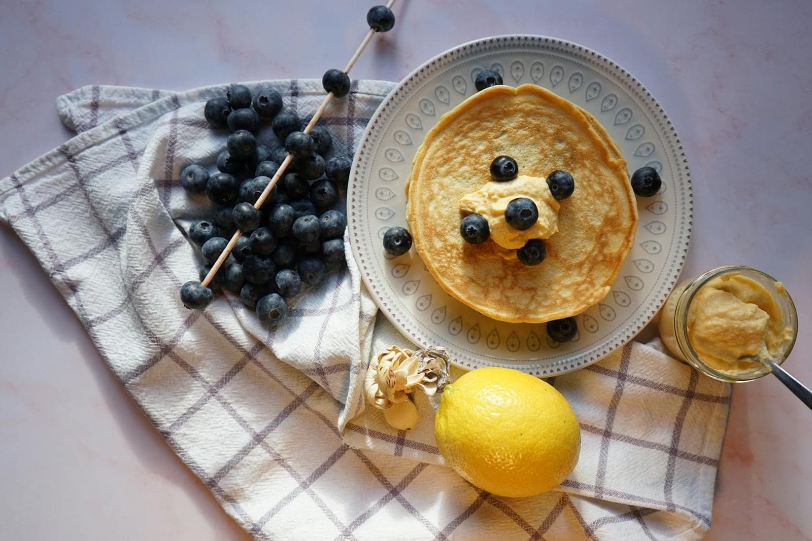 Lemon blueberry ricotta pancakes with blueberries, lemon, honey, and butter on a table