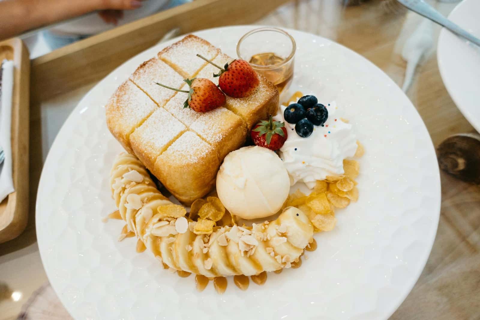 Caramelized banana French toast-style breakfast plate with berries, cream, and syrup
