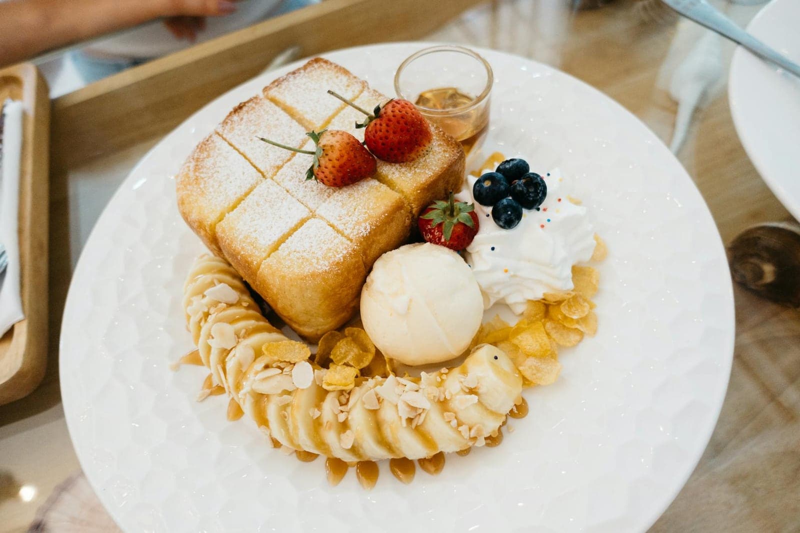 Caramelized banana French toast-style breakfast plate with berries, cream, and syrup