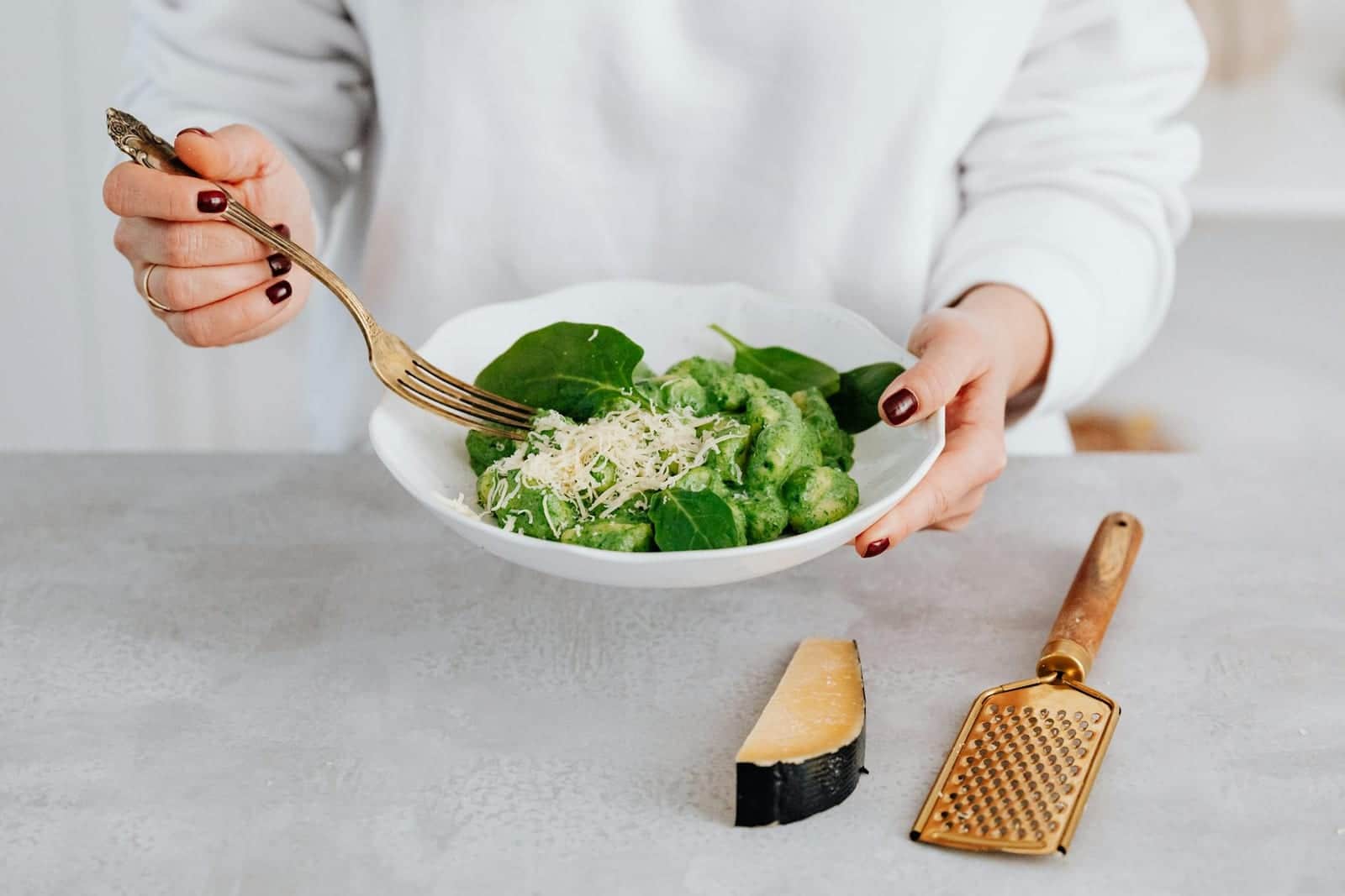 Cauliflower gnocchi-style pasta with green pesto, spinach, and grated cheese