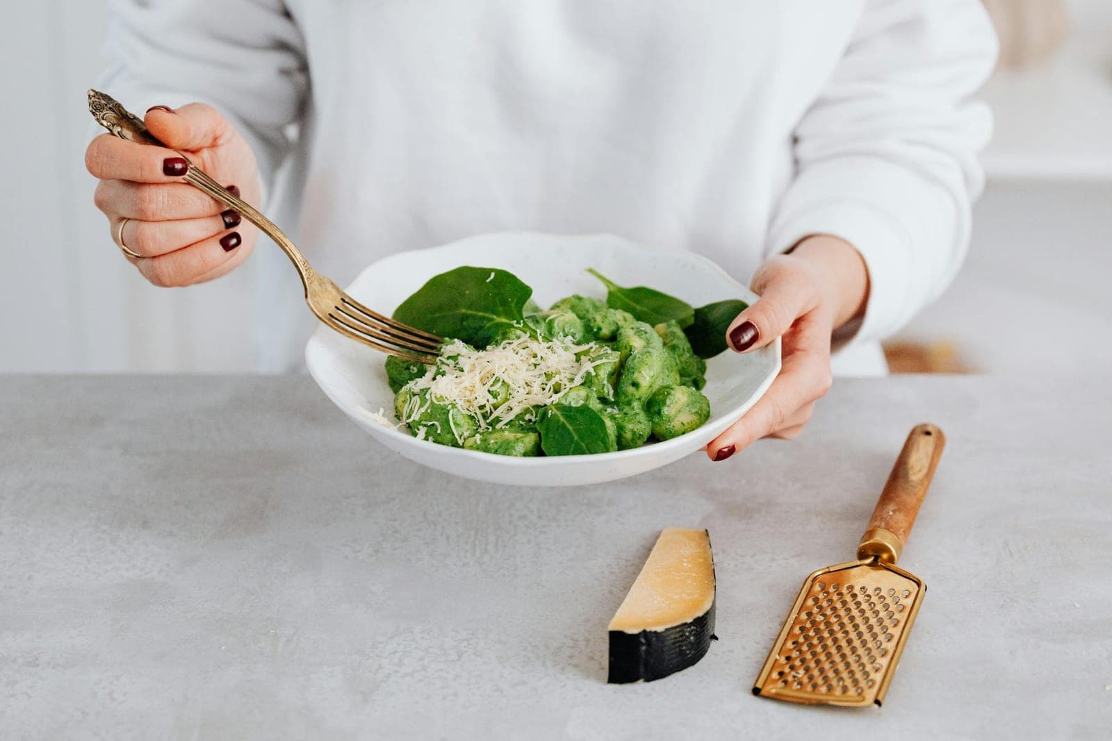 Cauliflower gnocchi-style pasta with green pesto, spinach, and grated cheese