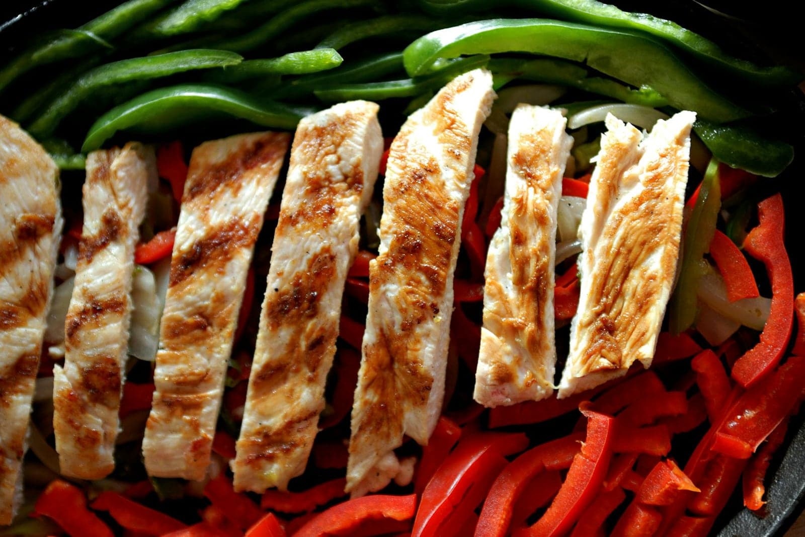 Chicken fajita meal prep with sliced grilled chicken, peppers, and onions