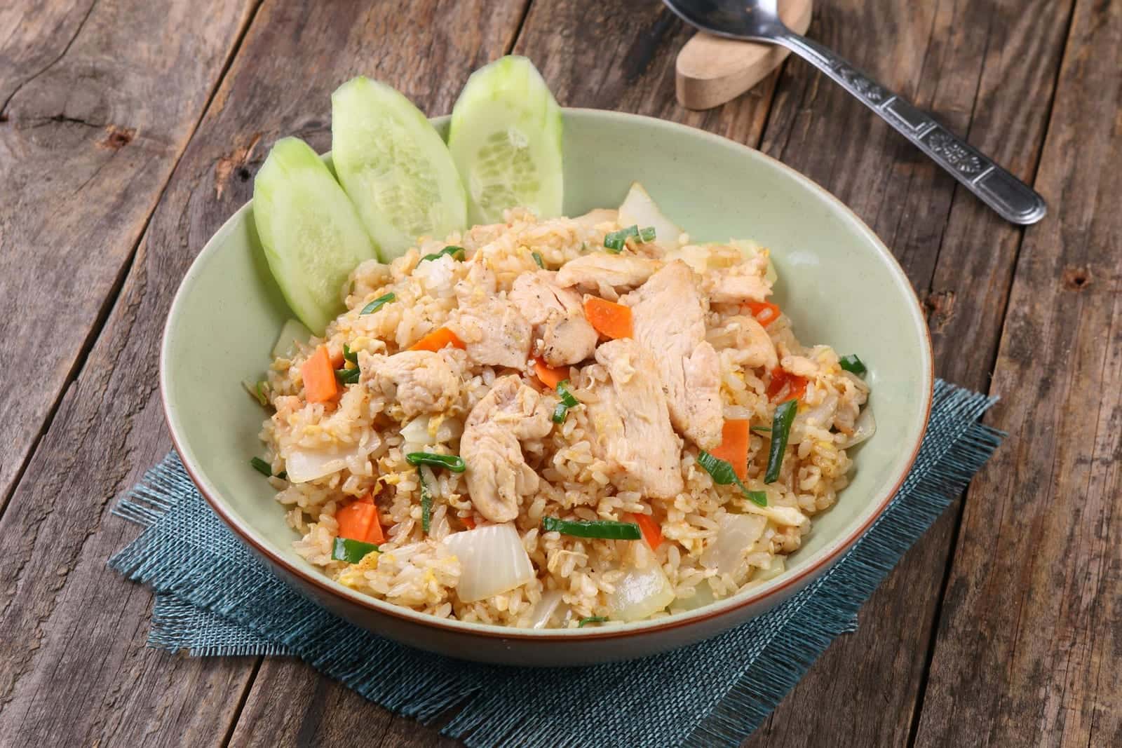 Chicken fried rice with diced chicken, vegetables, and rice in a green bowl