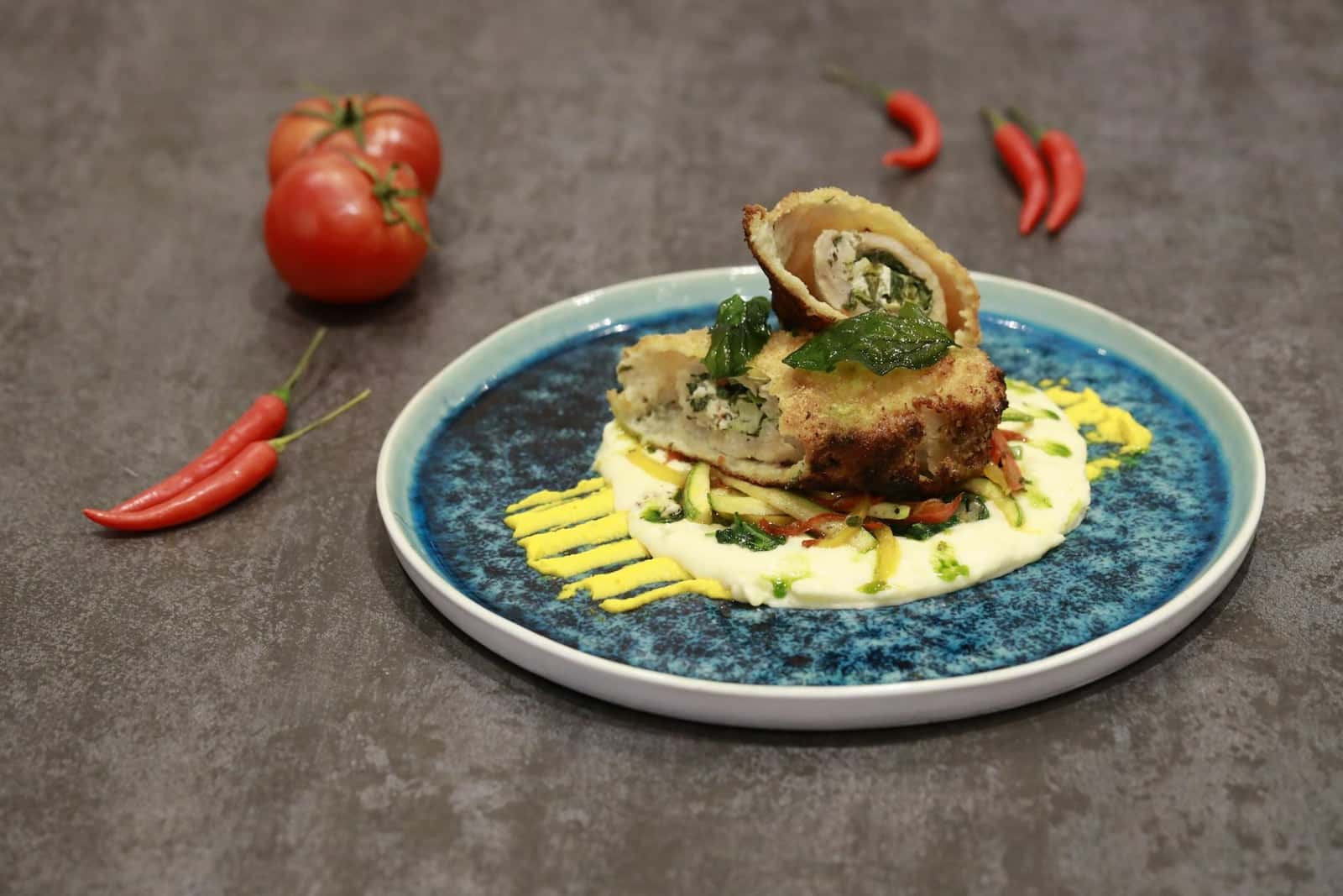 Chicken Kiev-style breaded chicken served with sauce and garnish on a ceramic plate