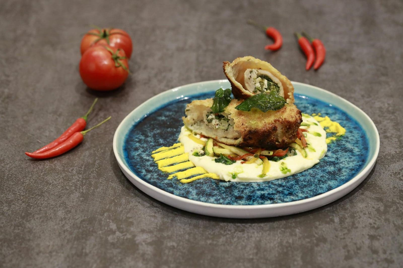 Chicken Kiev-style breaded chicken served with sauce and garnish on a ceramic plate
